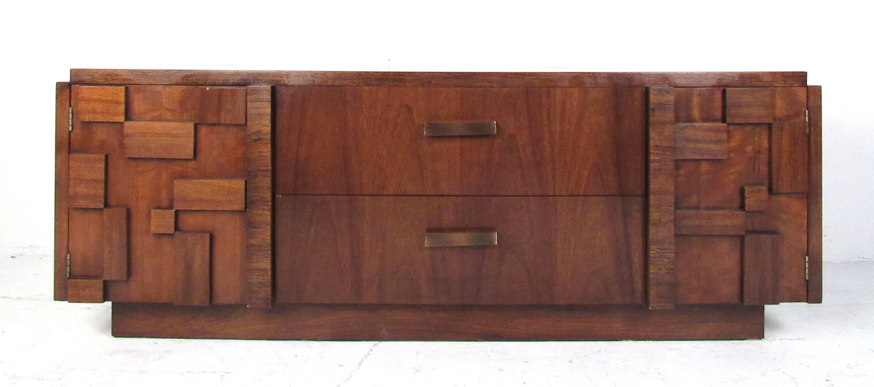 This gorgeous vintage modern credenza offers plenty of room for storage within its two hefty drawers and two large compartments with shelves. Quality construction with brutalist cabinet door fronts and sculpted drawer handles. This midcentury case