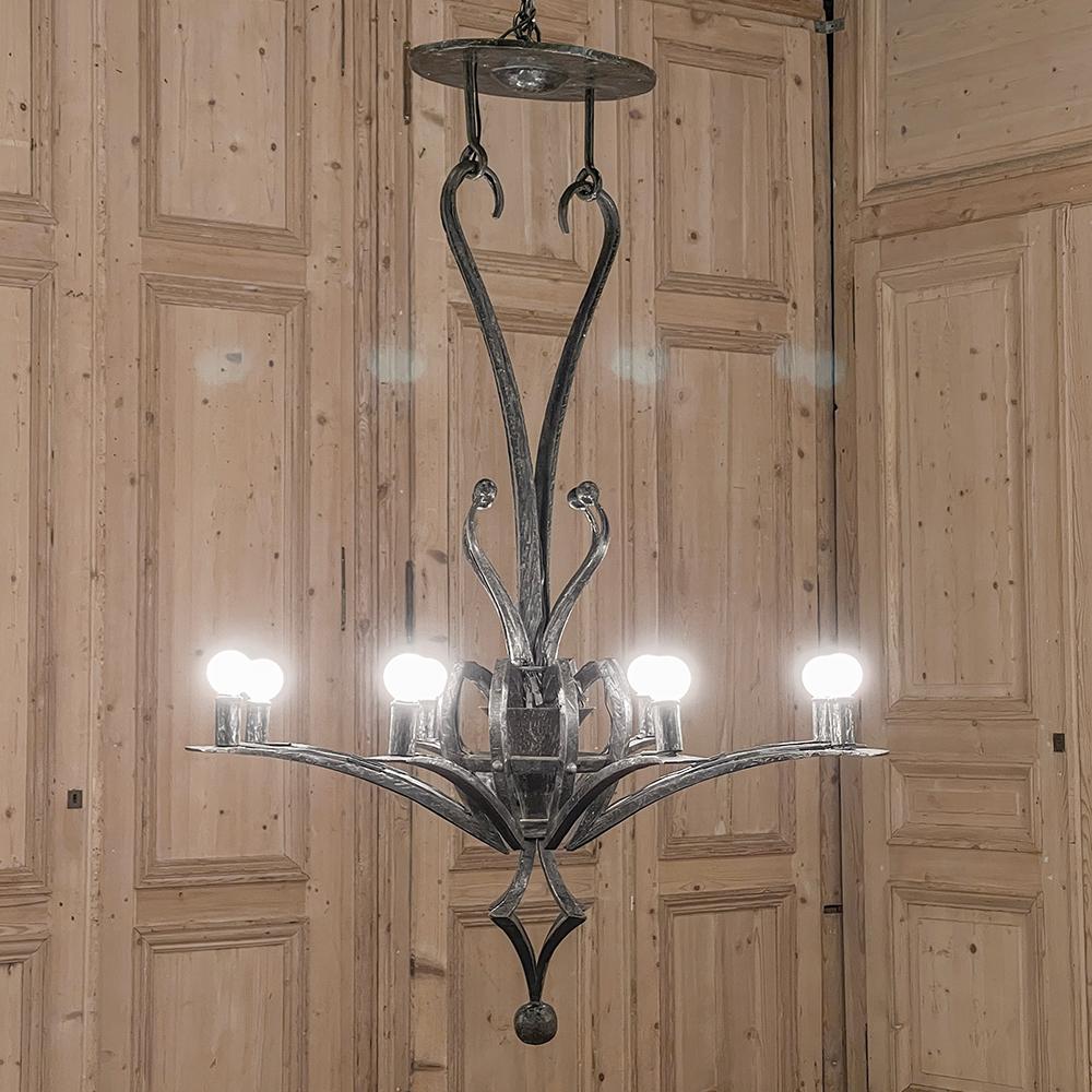 Mid-Century Modern Brutalist Wrought Iron Chandelier is a study in unique forms, with an intriguing double-support in the shape of a heart connecting to two ceiling mounts which prevents spinning. The bobeches rest atop reverse-curved arms, with a