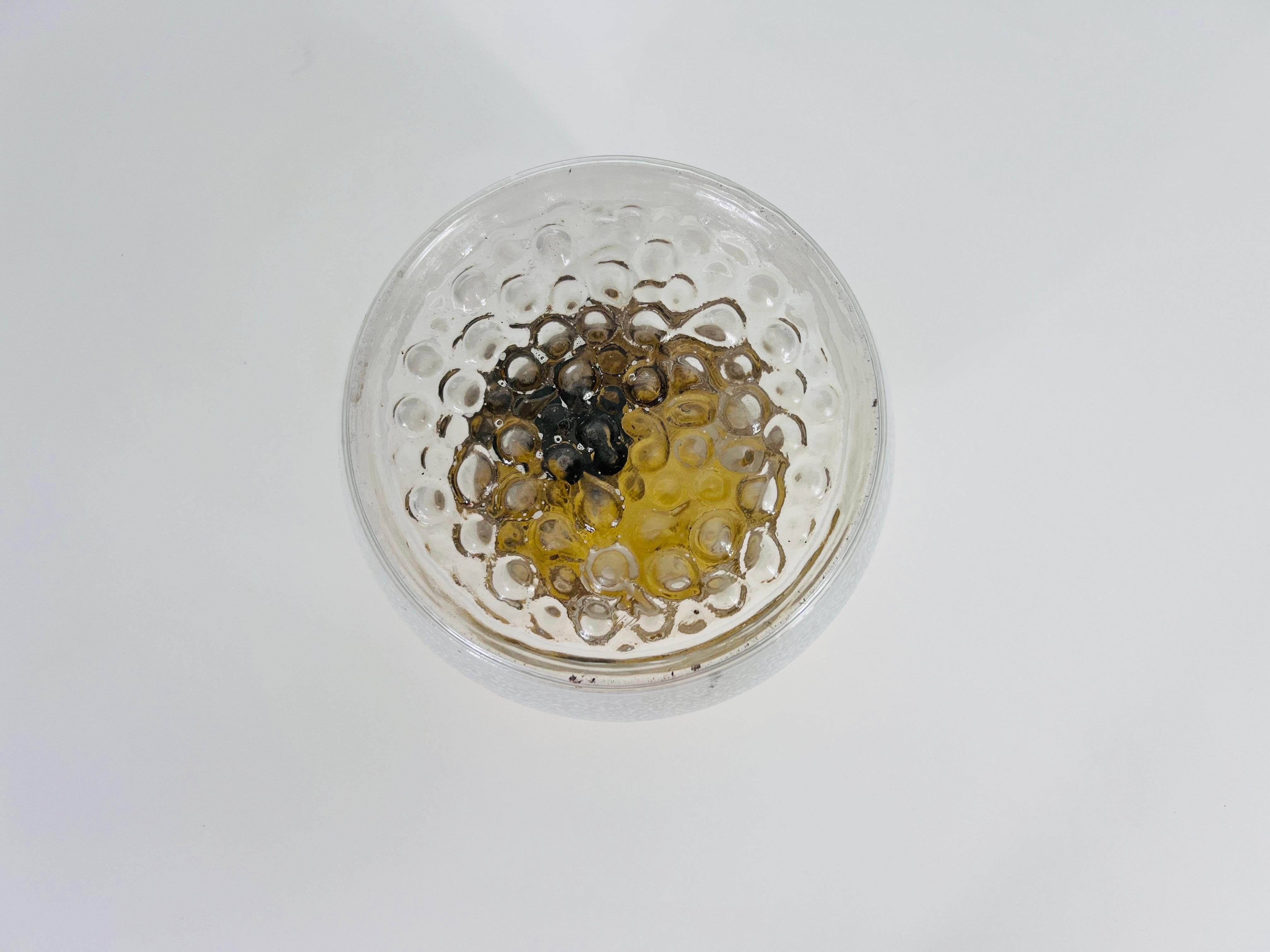 Cette applique encastrée fabriquée par la célèbre marque VEB de Dresde, en Allemagne de l'Est, est un exemple stupéfiant de design du milieu du siècle. La lampe présente un verre soufflé à la bouche avec une texture de bulle captivante, ajoutant une