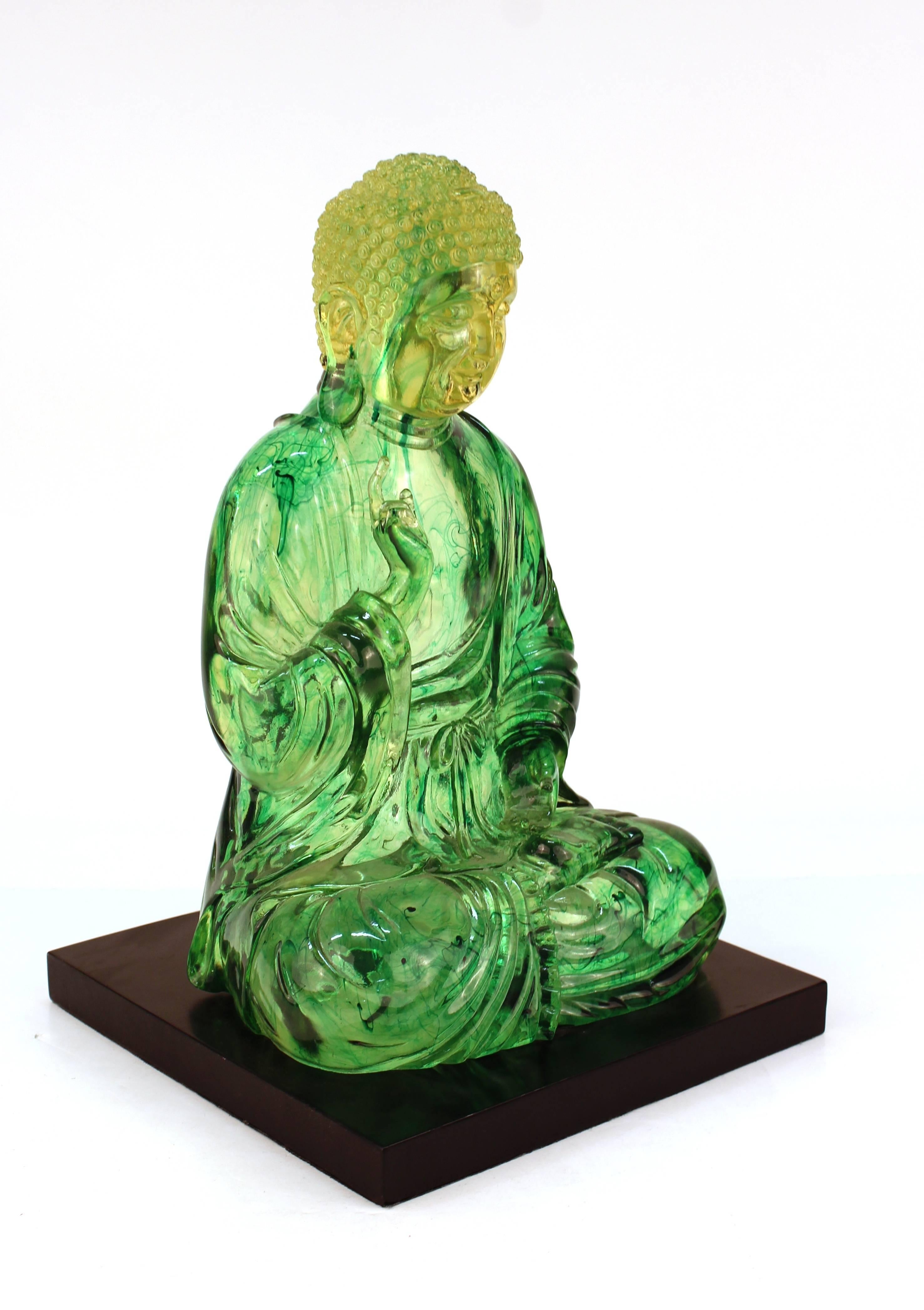 Sculpture de Bouddha datant du milieu du 20e siècle. Fabriqué en résine transparente avec une ombre jaune à verte et des inclusions vert foncé. La sculpture repose sur une base carrée avec une finition noire brillante. Portez des vêtements adaptés à