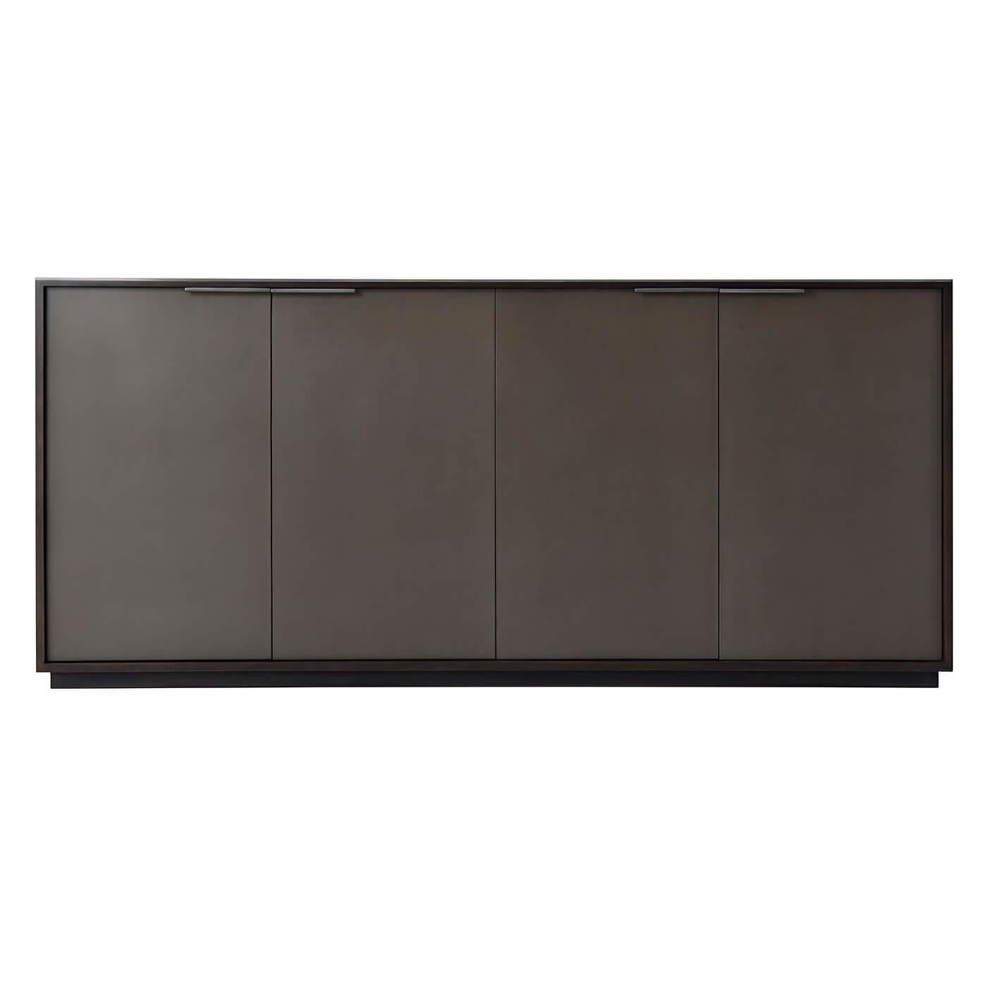 Mid-Century Modern style four-door buffet with an Ossian finish cherry case, four grey leather paneled doors enclosing two sections each with an adjustable shelf, and a gunmetal finish top molding and handles. 

Dimensions: 76