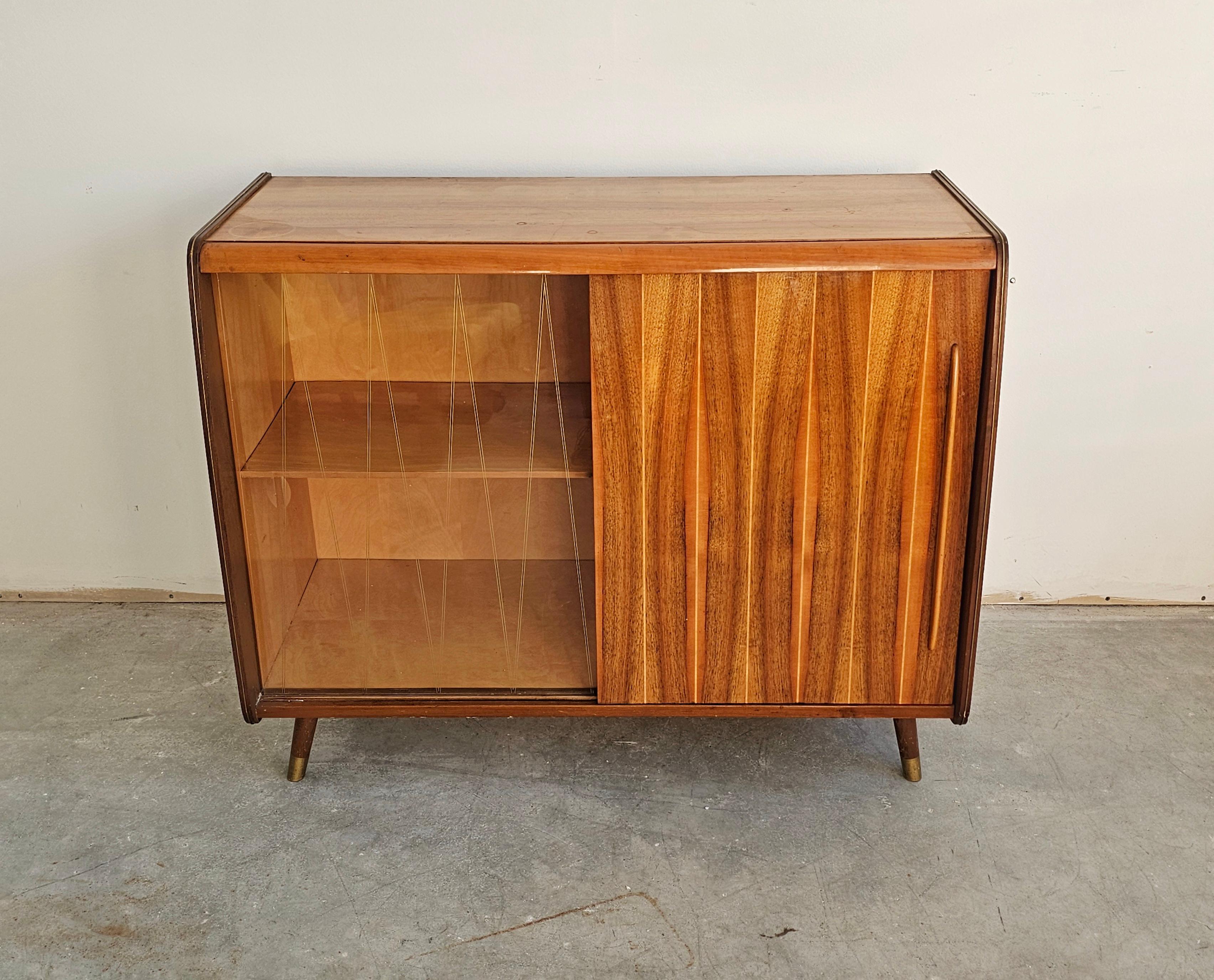 In this listing you will find a fabulous Mid Century Modern buffet or a small vitrine done in walnut. The buffet has two doors, one done in walnut and the other in glass with diamond pattern on it. Each compartment has a shelf, making this piece