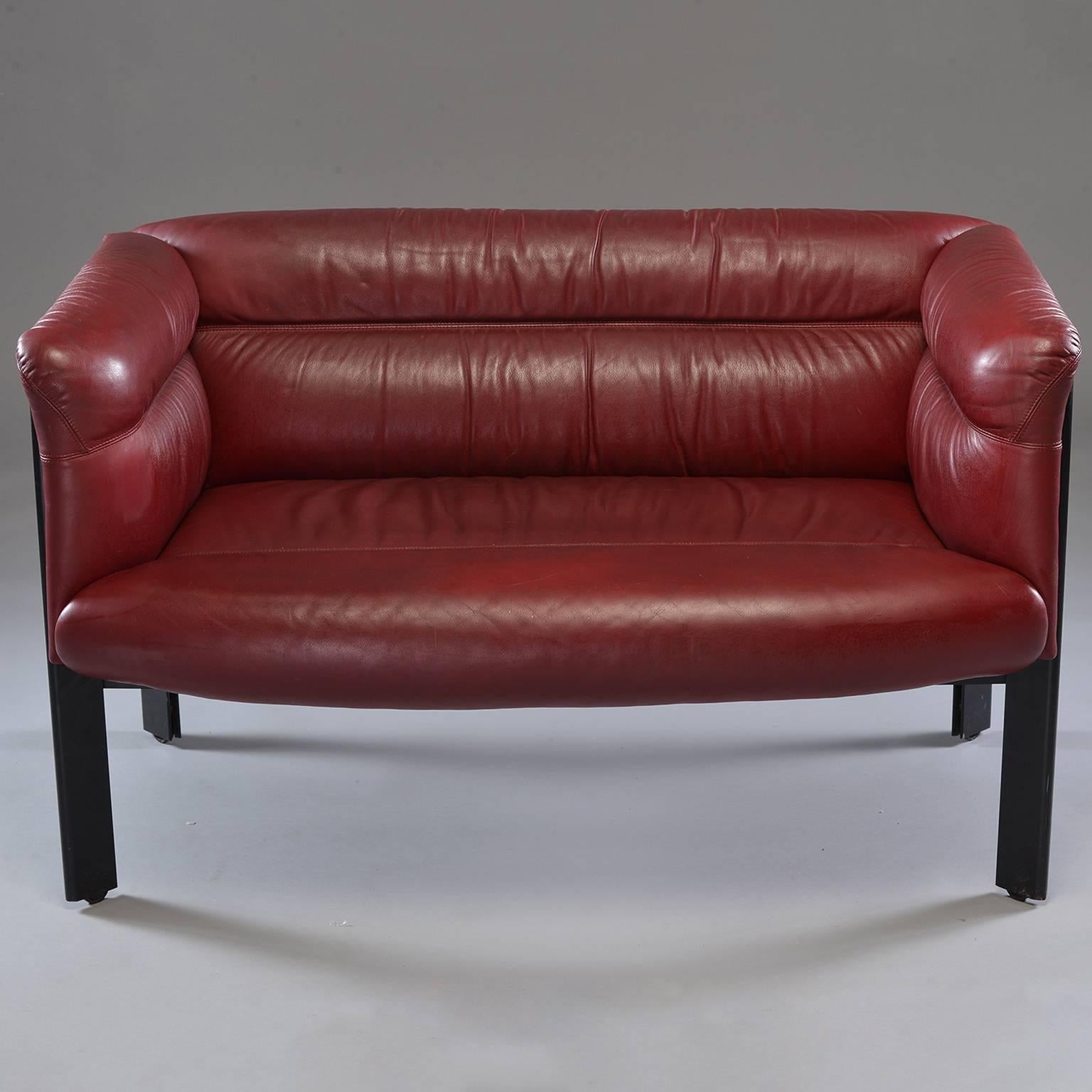 Burgundy leather settee by Italian maker Poltrona Frau, circa 1970s. Black metal legs have casters. Leather on back is marked by maker. 
