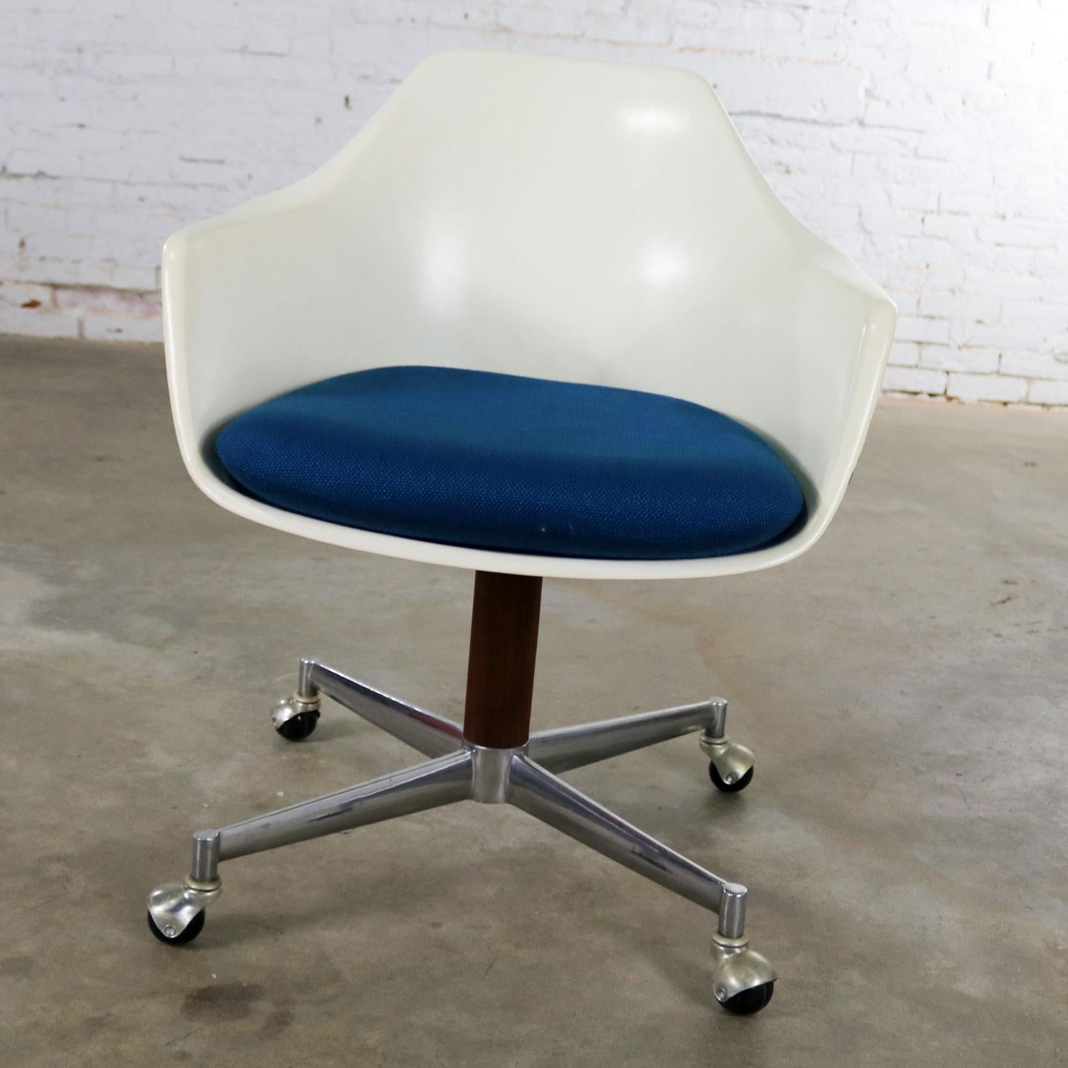 Handsome Mid-Century Modern rolling, swivel, and tilt office desk fiberglass shell armchairby Burke Inc. with a royal blue seat cushion and wood veneered steel shaft. It has the big Burke B and the number 116 embossed on the bottom along with Burke