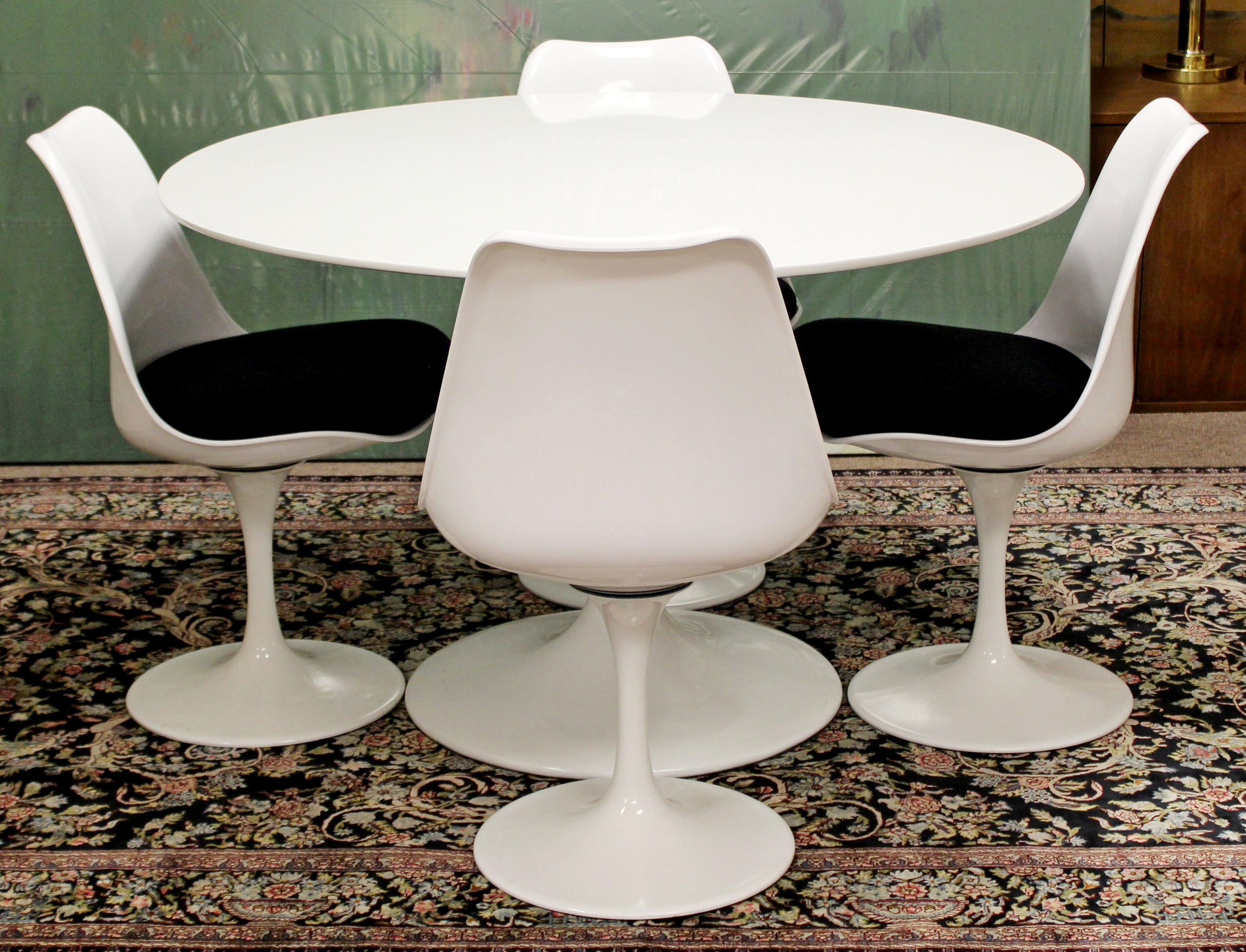 For your consideration is a fabulous, white, tulip dining set, with four chairs, in the style of Eero Saarinen, by Burke, circa the 1960s. In very good condition. The dimensions of the table are 47.5