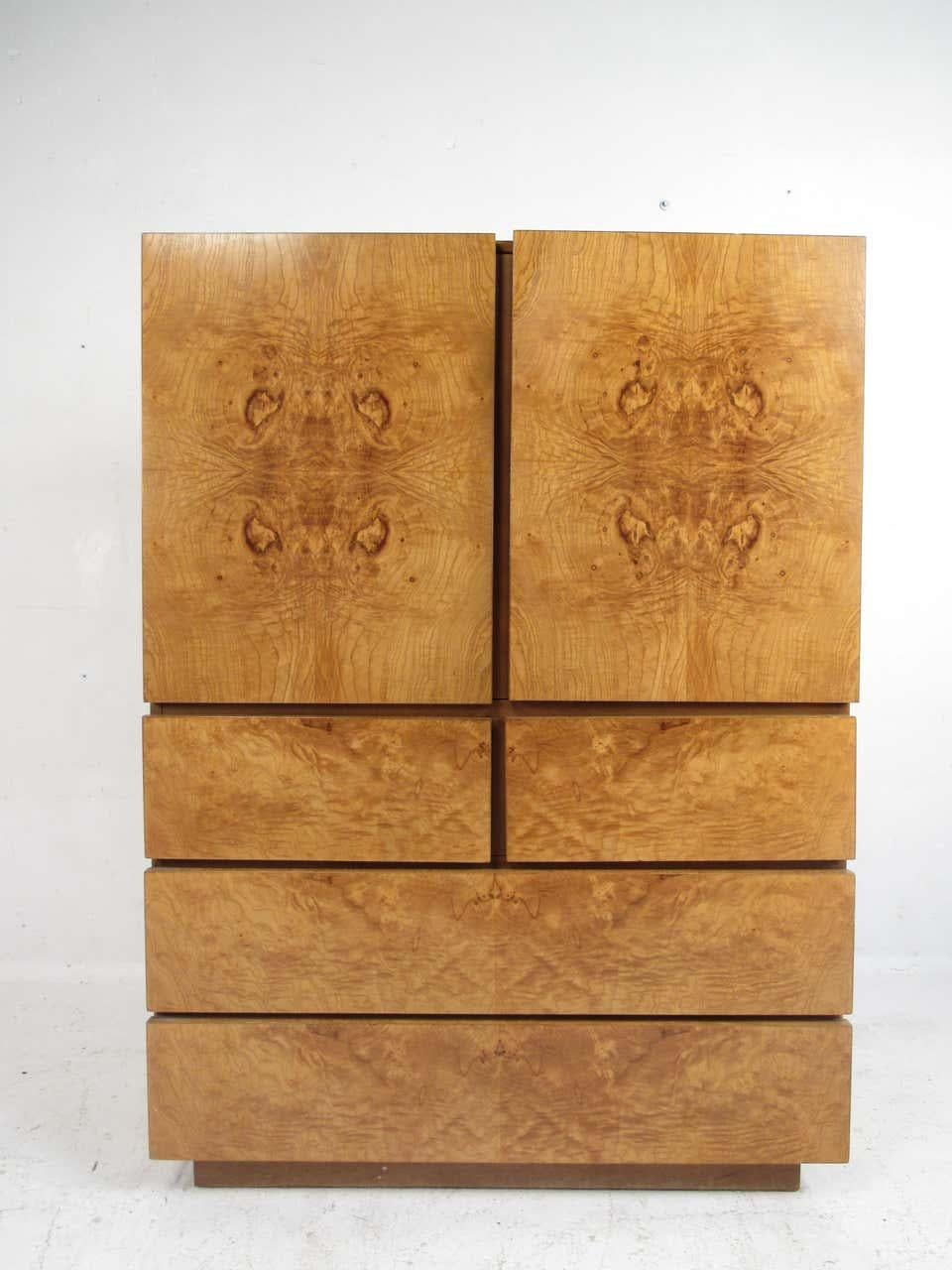 This impressive vintage modern highboy dresser. Well-made case piece with straight lines and an elegant burl wood grain throughout. A gently used wardrobe/armoire with a storage compartment on top hidden by two cabinet doors. This Milo Baughman