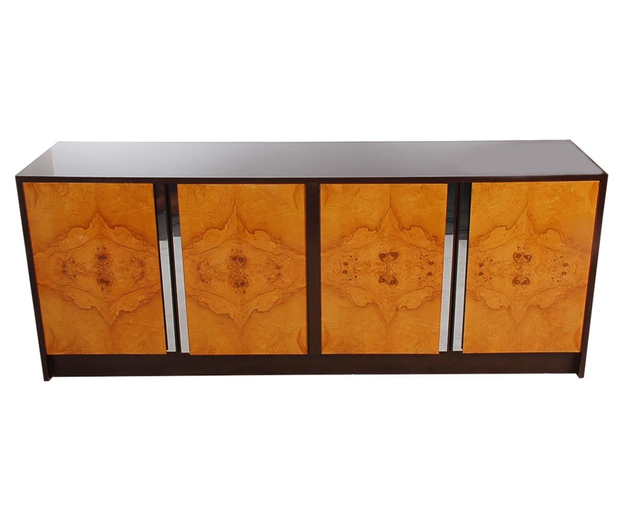 A handsome looking 4-door credenza in the manner of Milo Baughman or Pierre Cardin, circa 1970s. It features a glossy chocolate brown case with beautiful contrasting olive burl doors.
