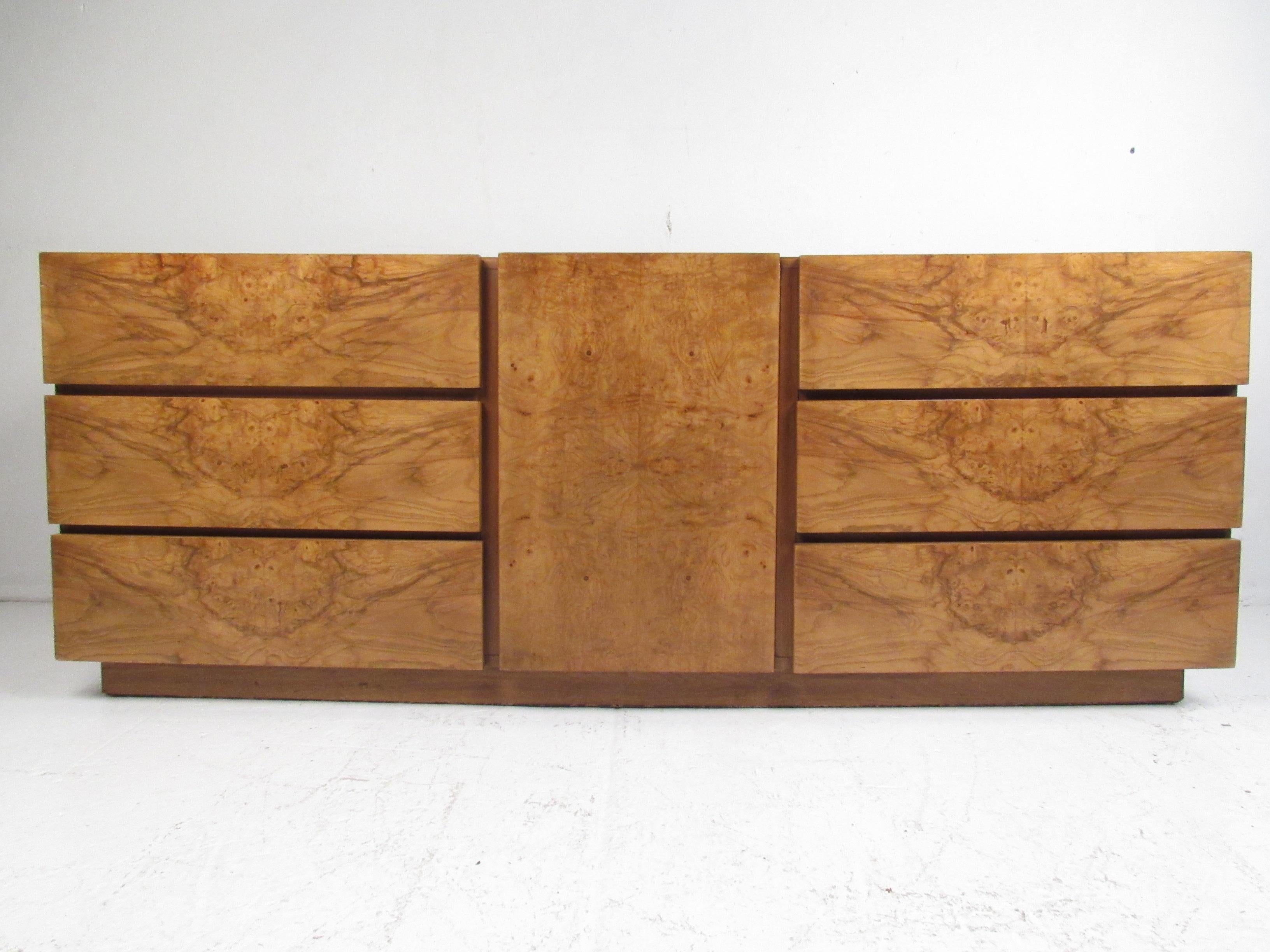 This stunning vintage modern dresser features nine hefty drawers ensuring plenty of room for storage. A lovely straight line design with an elegant burl maple finish and three drawers in the centre hidden by a cabinet door. This stylish midcentury