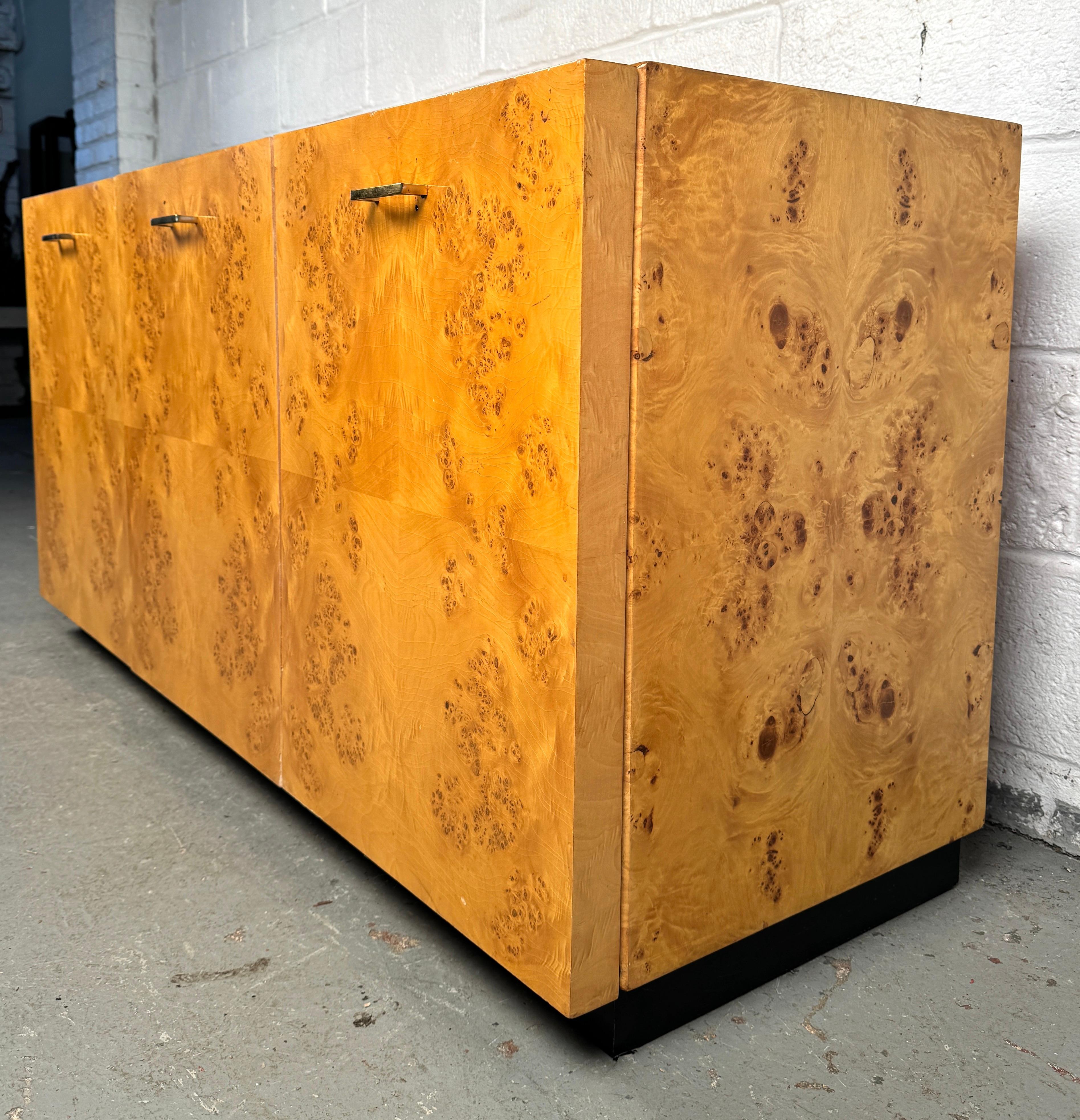 Credenza moderna di metà secolo in legno di radica nello stile di Milo Baughman e Arthur Umanoff, caratterizzata da una ricca impiallacciatura di radica in tinta con il libro, linee minimaliste e una base scultorea in metallo. Un pezzo senza tempo