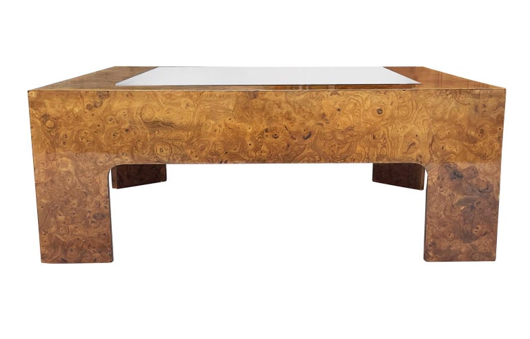 A stunning coffee table from the 1970's. It features beautiful figurative burl wood, with clear glass inlayed top.