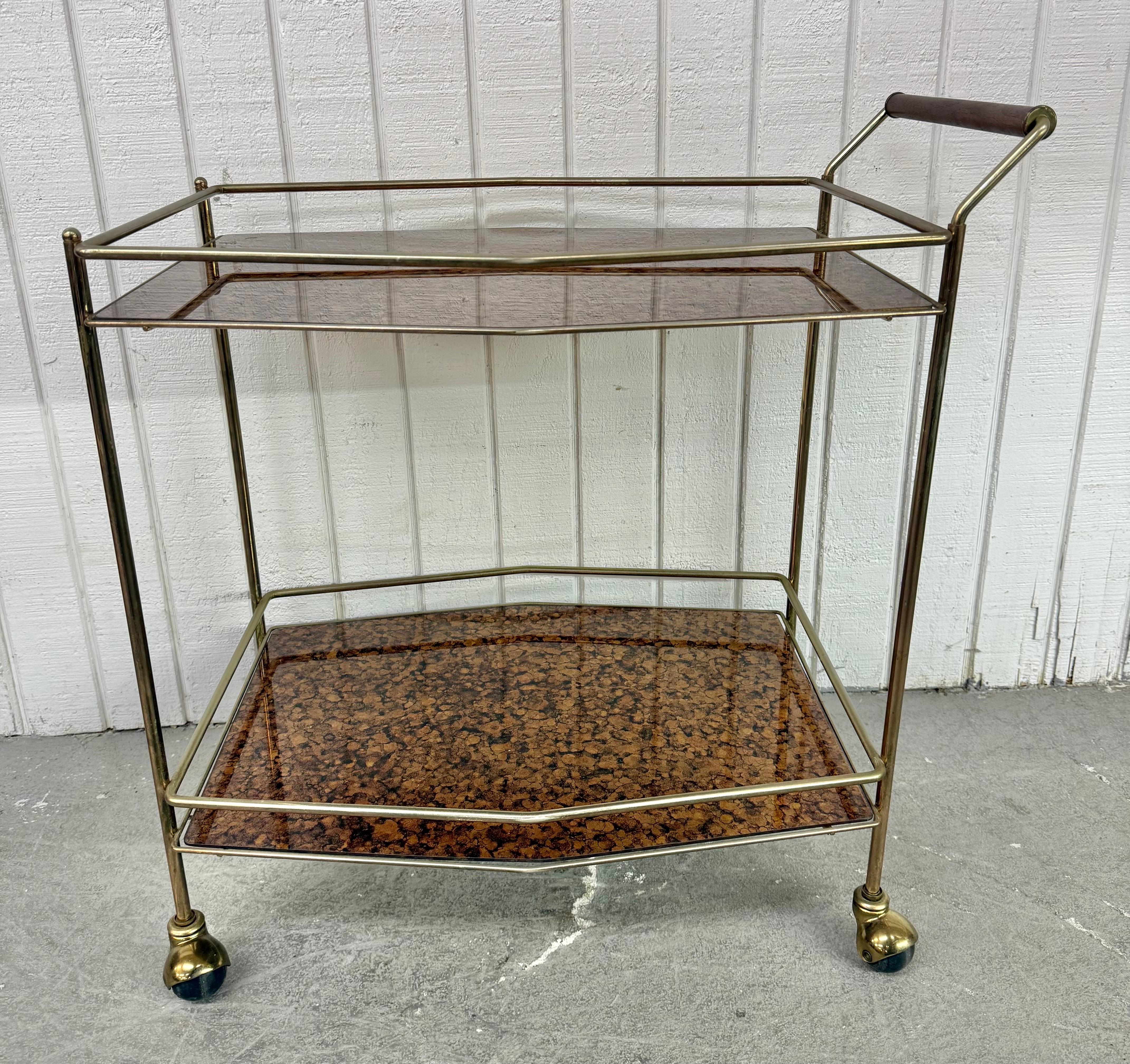 Dieses Angebot ist für eine Mid-Century Modern Burled Brass Serving Cart. Ausgestattet mit einem Messingrahmen, einem Griff aus Nussbaumholz, zwei Einlegeböden aus gewölbtem Glas und originalen Rollen für den Transport. Eine außergewöhnliche