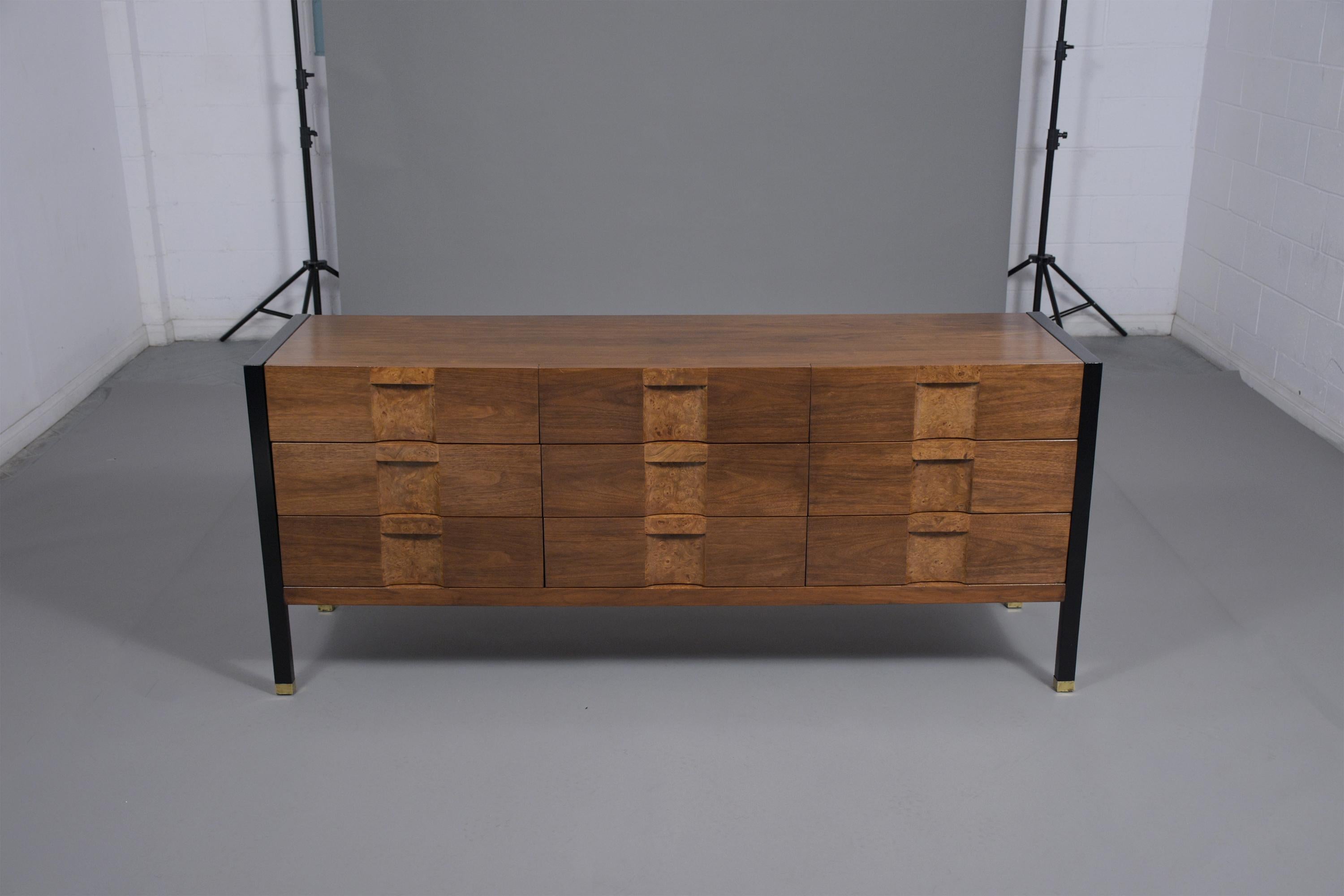 A fully restored mid-century chest of drawers hand-crafted out of walnut wood features a newly stained walnut and ebonized color combination with a lacquered finish. The dresser comes with nine pullout drawers with burled veneer details that open