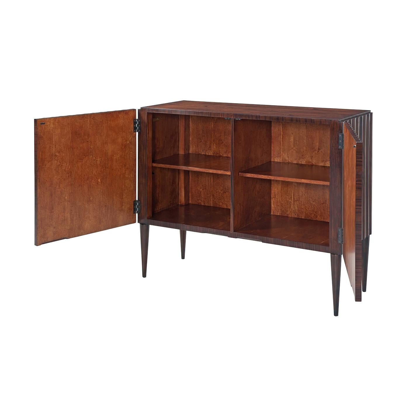 A fine midcentury style cabinet with fluted sides of morado, sycamore and mahogany with an interior fit with shelves and raised on turned and tapered legs.
Dimensions: 47.5