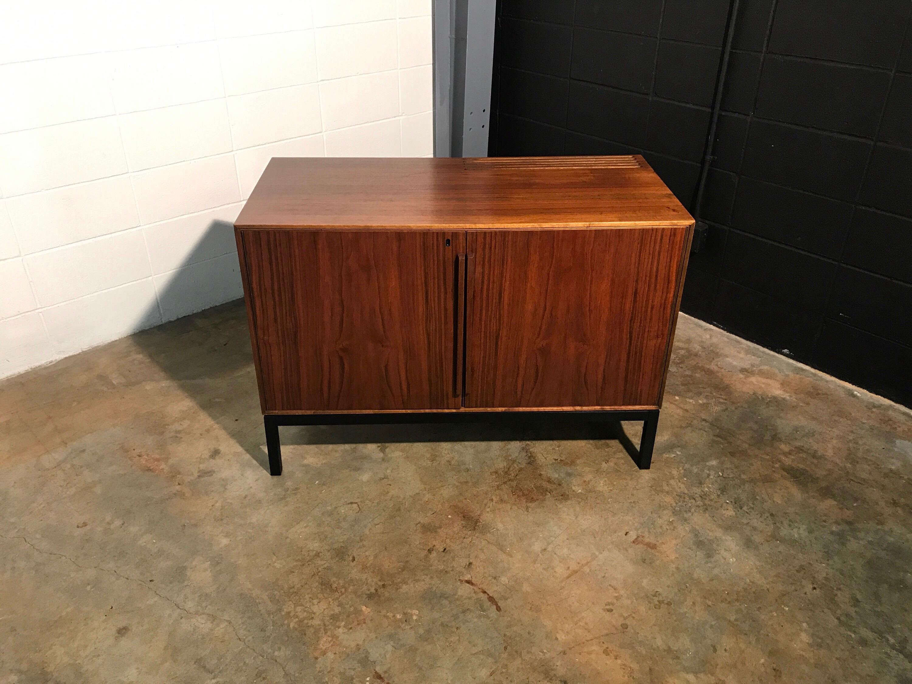Rare to see Mid-Century Modern two-door cabinet with built-in refrigerator. Beautiful walnut cabinet features slim sculpted handles and an ebonized base. Plenty of storage on the left side with shelving to accommodate tall bottles and shelves on the