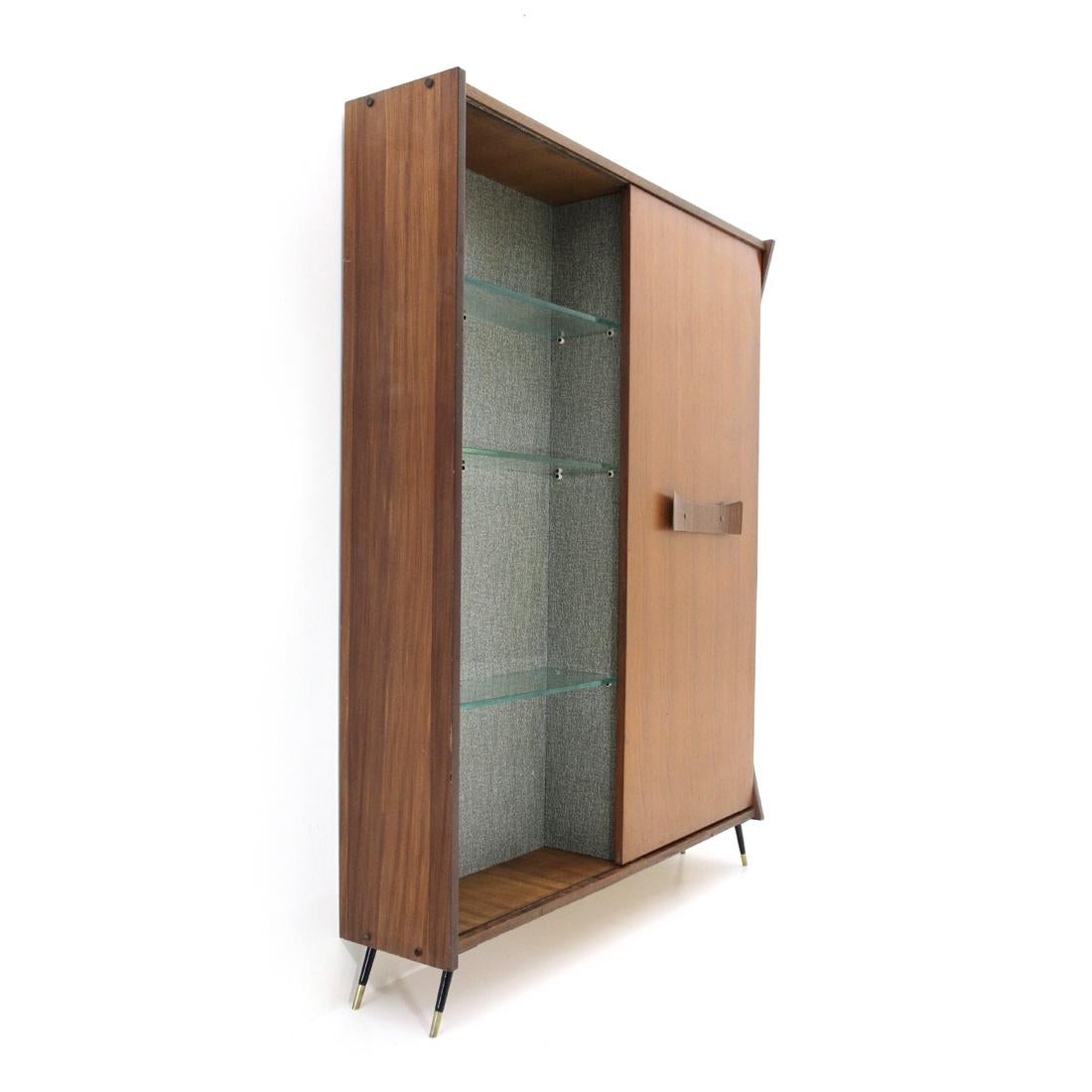 Italian manufacturing cabinet produced in the 1950s.
Teak veneered wood structure.
Interior lined with plastic film.
Left compartment with glass shelves.
Right compartment with wooden shelves and drawer, round mirror and lamp with white opal