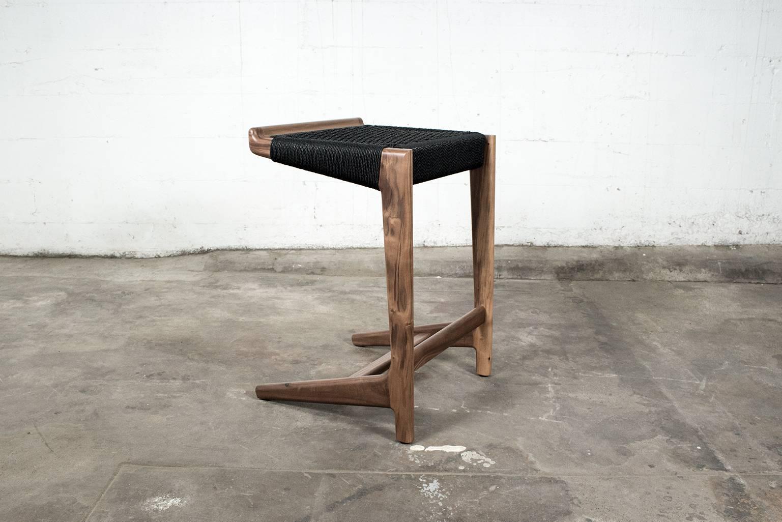 Sgabello a sbalzo Rian in legno di noce e corda danese nera, ispirato alla metà del secolo scorso. Può essere realizzato con qualsiasi legno duro nazionale o esotico a tua scelta. La corda danese è disponibile in tre colori: Kraft, Bianco e Nero. La