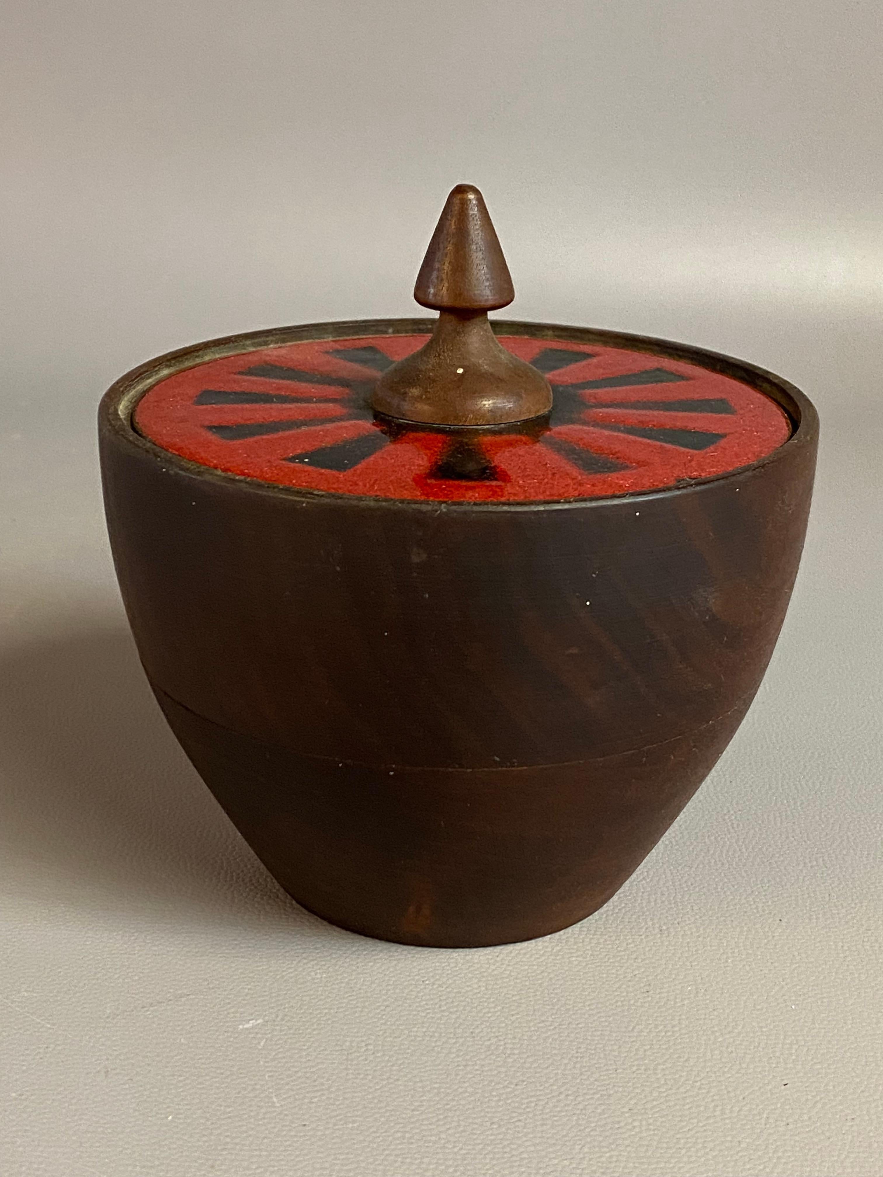 Hand turned walnut and enameled covered vessel. It still retains its BIG red label on the bottom, Capital Enterprise Company, New York 1, N.Y. Circa 1960.  A radiating sun like pattern in black and vermillion enameling with a walnut finial tops off