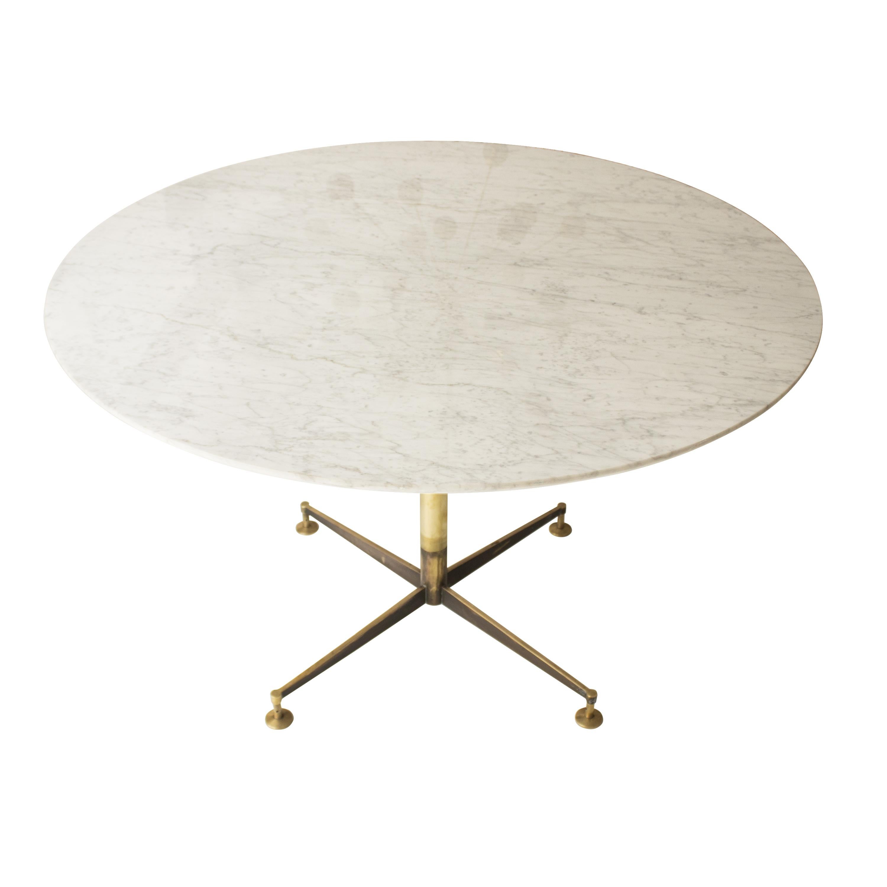 Italian Mid-Century Modern marble table from the 1950s.
The table is made up of a central brass foot with 4 legs, and leveling pads finished in aged brass.
The 2 cm thick round Carrara marble top with a flute peak edge finish rests on said