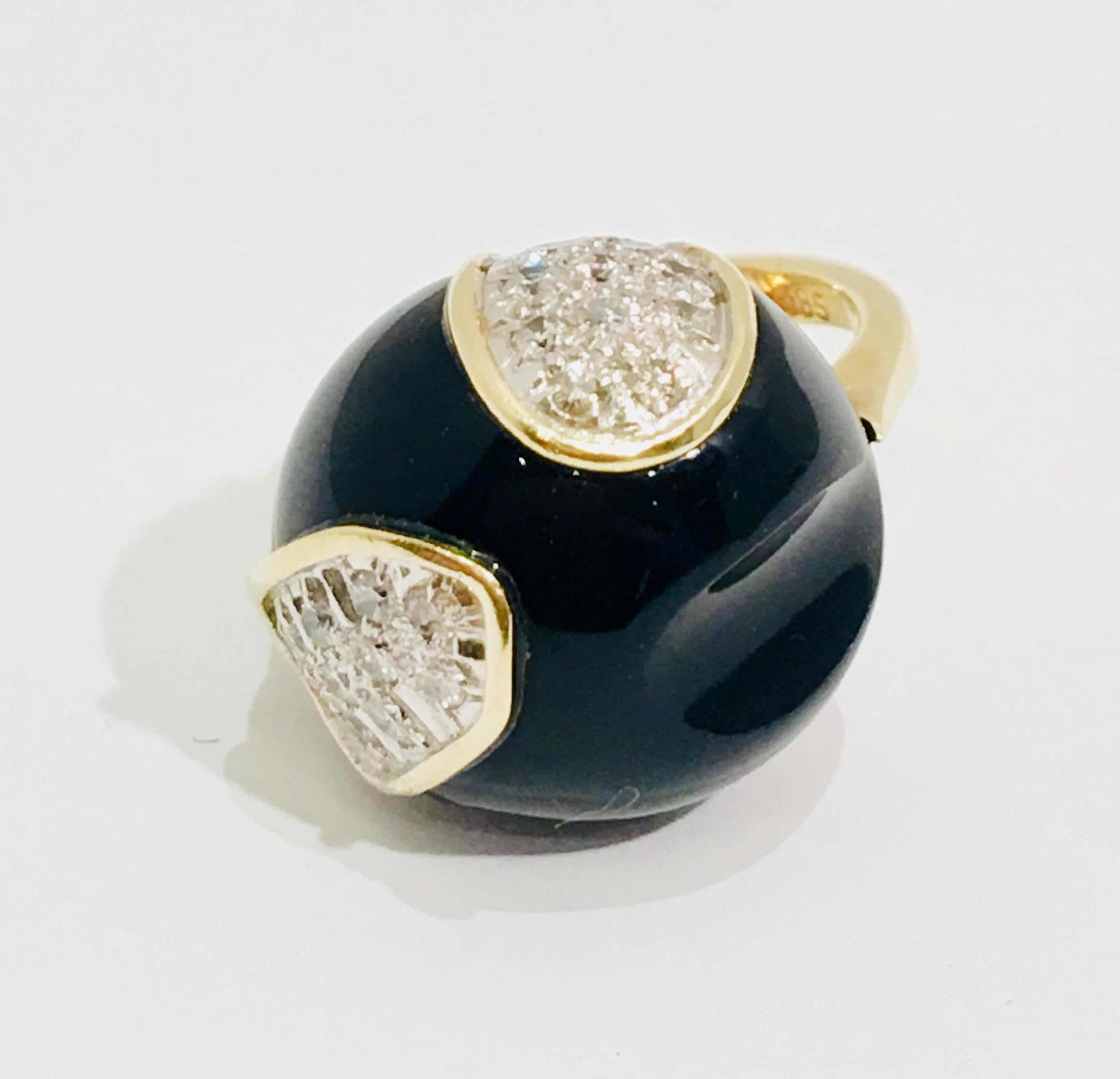 14 karat yellow gold ring from the 1960s features a bold, asymmetrically carved black onyx ball with 2 free form insets of brutalist textured 14 karat white gold and diamond pave rimmed in yellow gold.

20 round brilliant diamonds measure 2 mm in