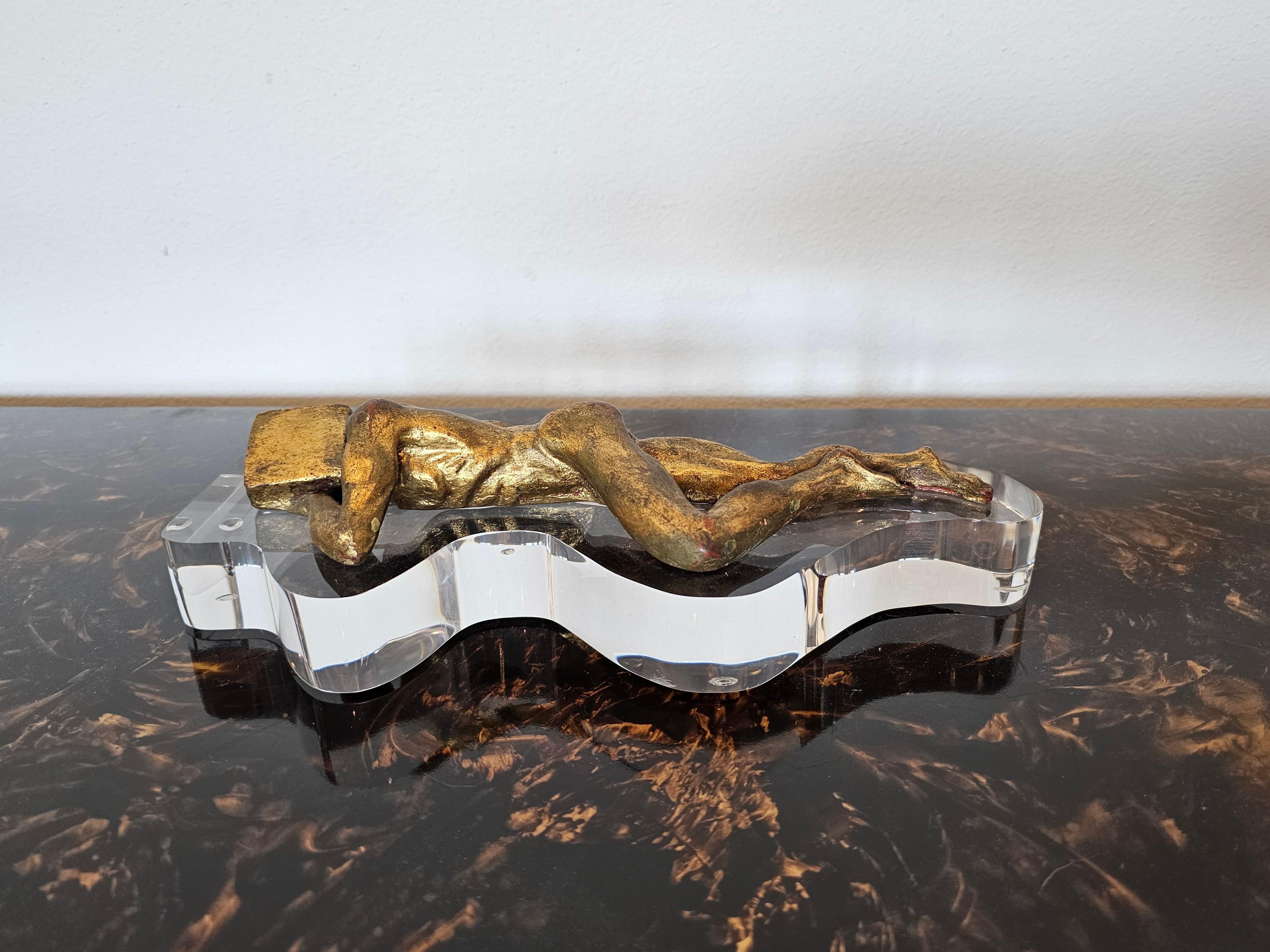 A fabulous mid-century modern hand carved giltwood sculpture, possibly American, depicting a surrealist nude figure of a man with block head lying in a prostrate position, mounted on a conforming clear lucite base. circa 1960

Dimensions: