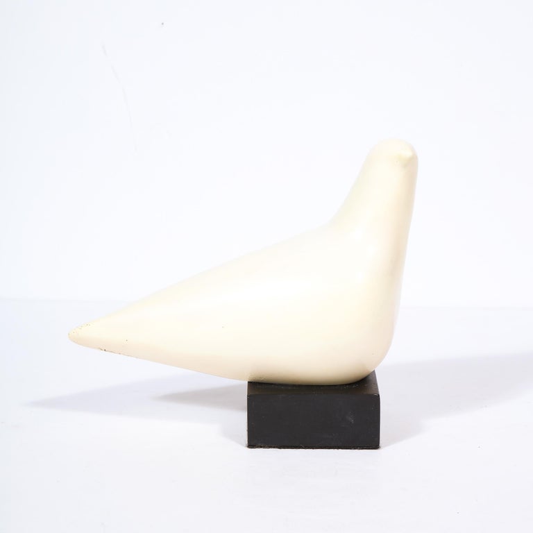 This elegant Mid-Century Modern sculpture was realized by the esteemed American artist Cleo Hartwig in the United States circa 1960. It offers a stylized dove in handcarved stone presented on a black enamel base. Recalling the iconic work of