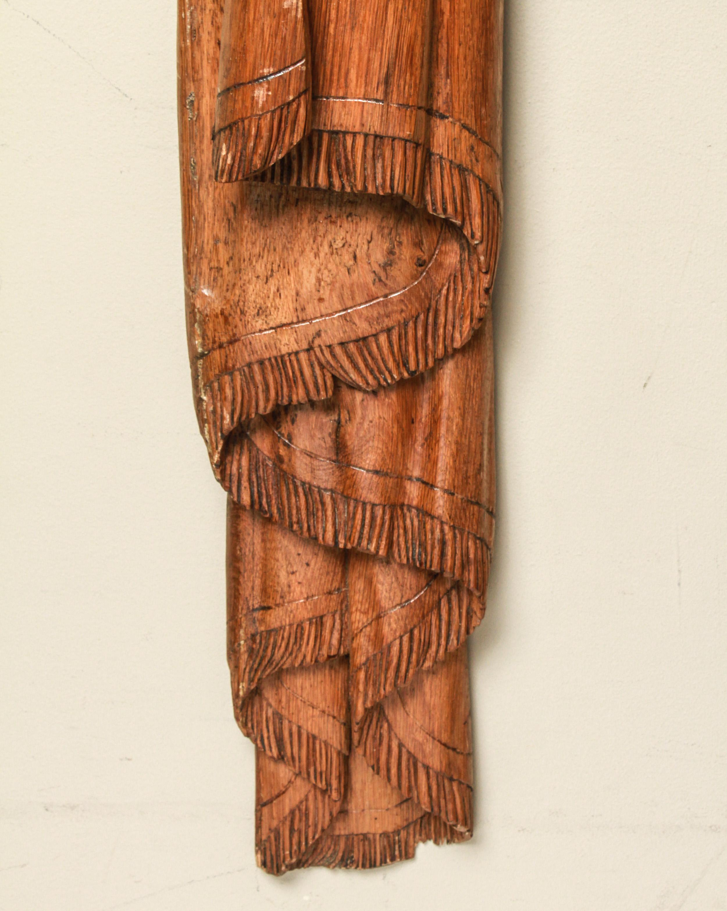 Mid-Century Modern carved wood wall sculpture depicting drapery or curtain swag with tassel. The piece is in great vintage condition with age-appropriate wear and a minor loss at the bottom, with light checking.