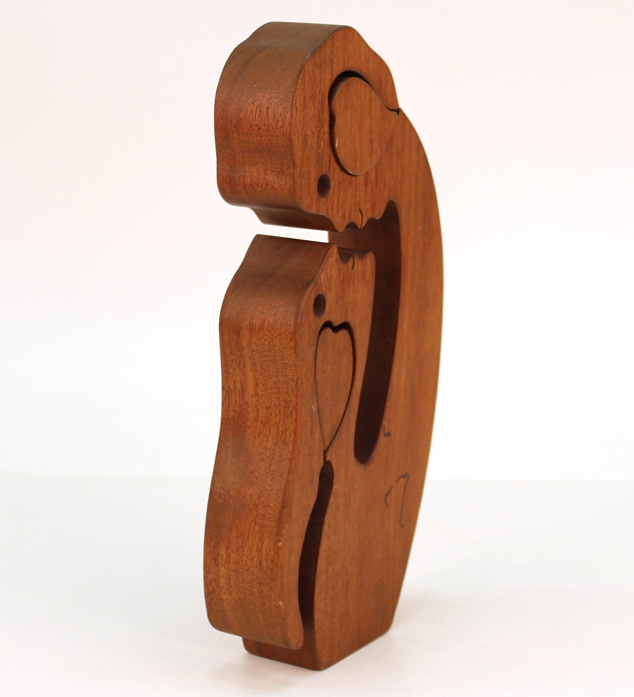 Mid-Century Modern geschnitzte Holzpuzzle-Skulptur in Form eines Paares, das sich in die Augen schaut, mit einer geschnitzten Herzeinlage, die entfernt werden kann. Das Stück hat Markierungsspuren auf der Rückseite. In gutem Vintage-Zustand.