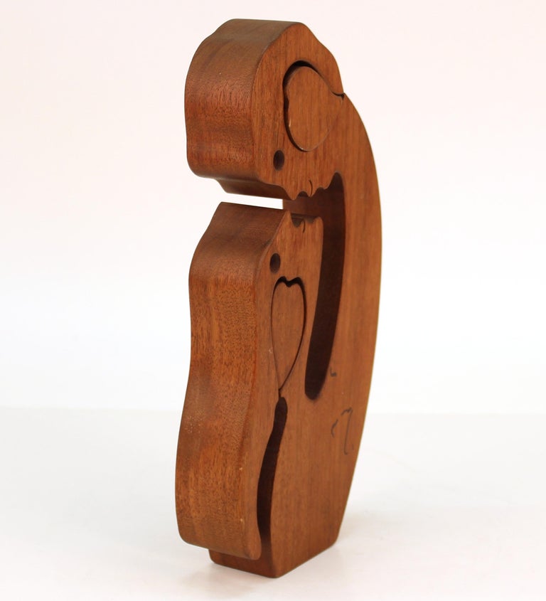 Mid-Century Modern carved wood puzzle sculpture in the shape of a couple gazing into each others eyes, each one having a carved heart inlay that can be removed. The piece has marker marks on the back side. In good vintage condition.