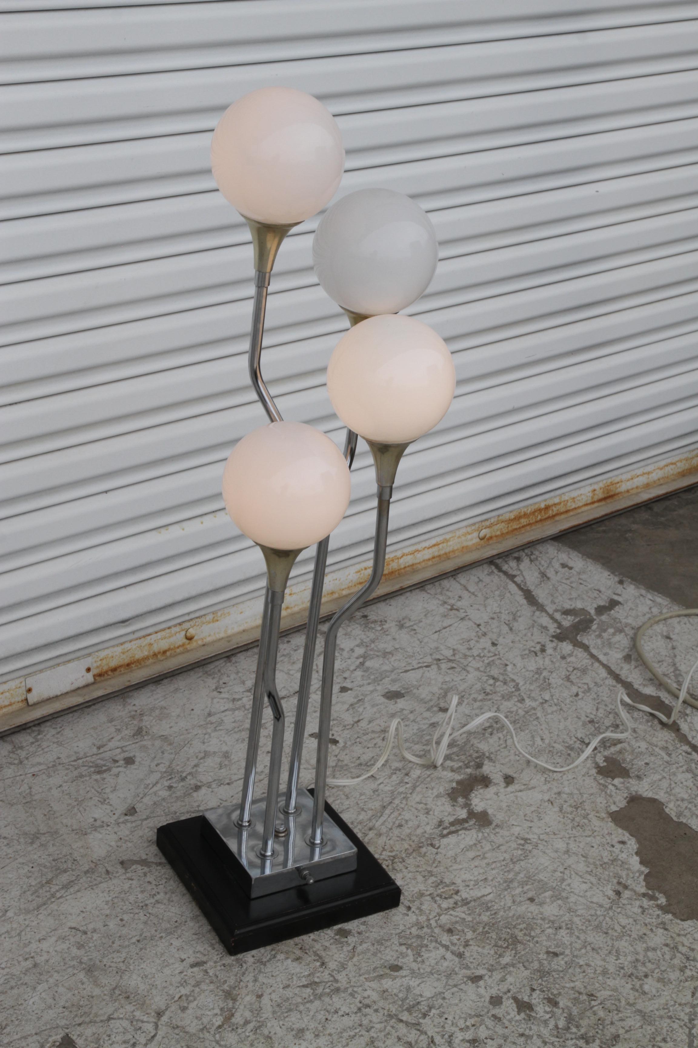 La lampada da terra Mid-Century Modern presenta quattro steli cromati a cascata su una base in metallo verniciato con 4 paralumi a globo in vetro lattiginoso. La lampada accende due lampadine alla volta e poi tutte e quattro.