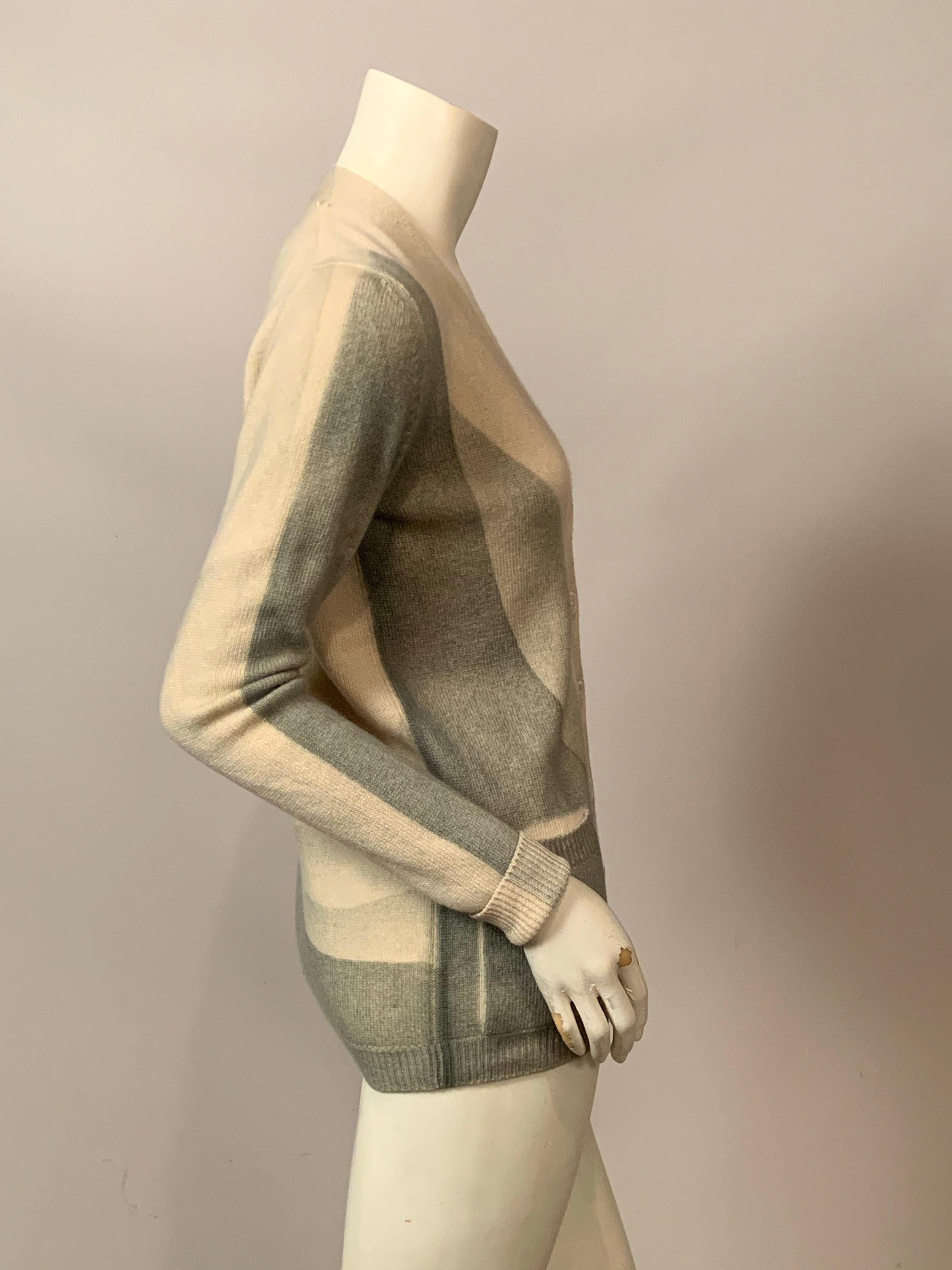 Questo cardigan in cashmere dal design Mid-Century Modern è un raro esempio di questo stile di design utilizzato per l'abbigliamento.  Il cardigan a due tasche e sei bottoni inizia in cashmere color crema all'altezza della scollatura e passa