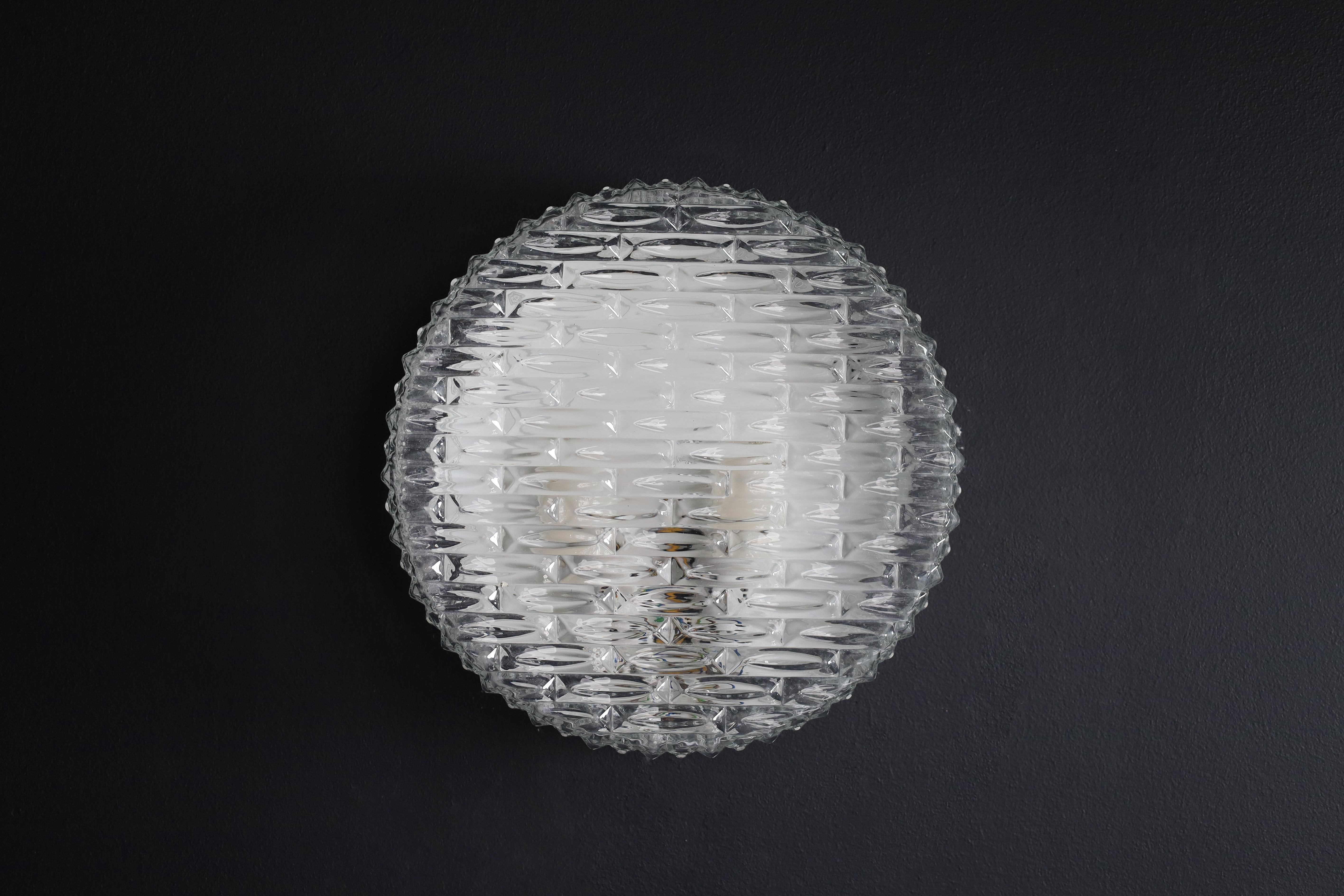 Round Ceiling or wall light Germany 1960s.

Round flush mount ceiling light or wall light made of heavy textured clear iced glass made in Germany, 1960s. This midcentury vintage lamp illuminates beautifully, casting a warm glow over a ceiling or