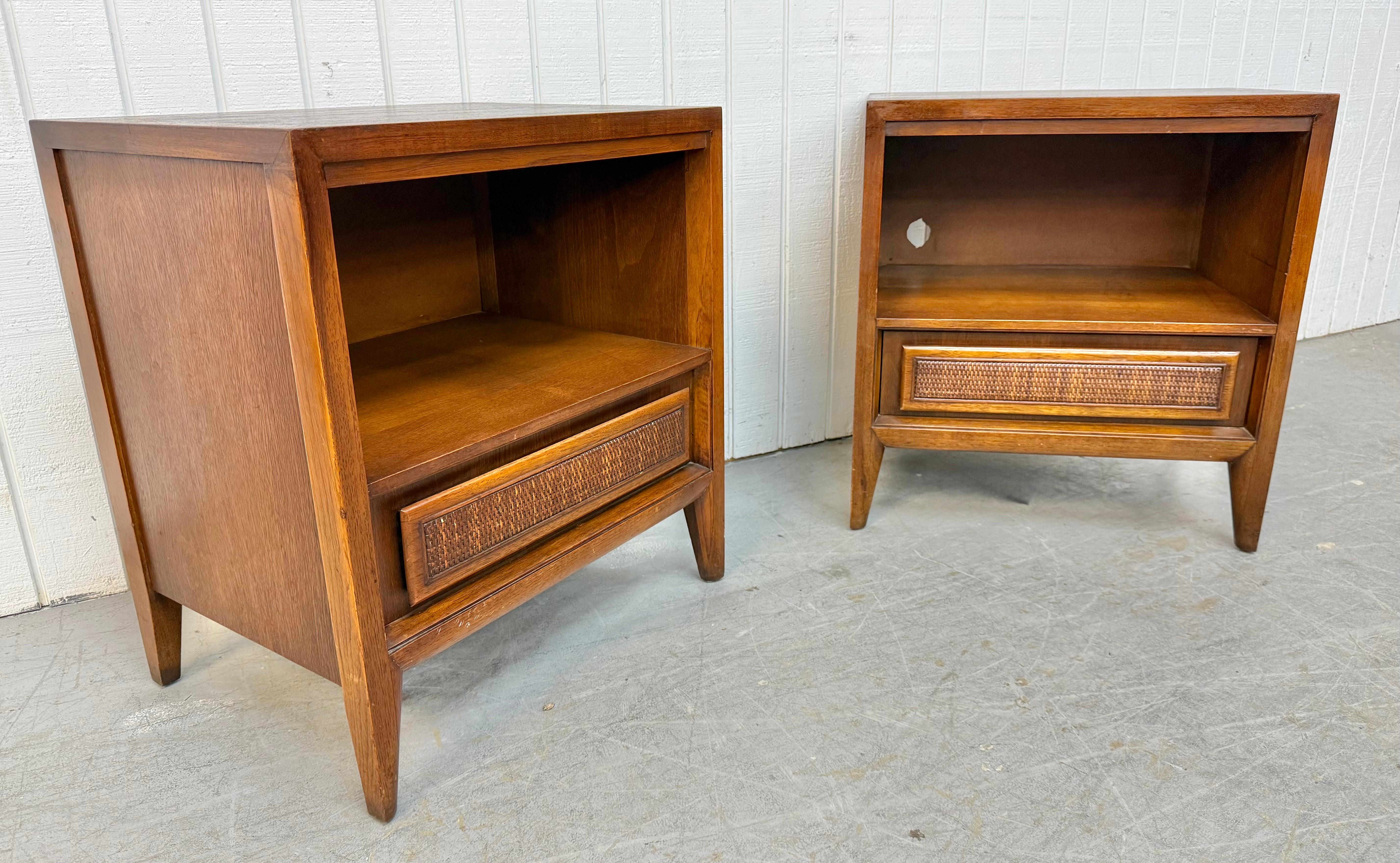 Questo annuncio si riferisce a una coppia di comodini in legno di noce della metà del secolo scorso. Caratterizzato da un design lineare, spazio aperto per riporre gli oggetti, cassetto singolo con frontale in canna, gambe moderne e finitura in