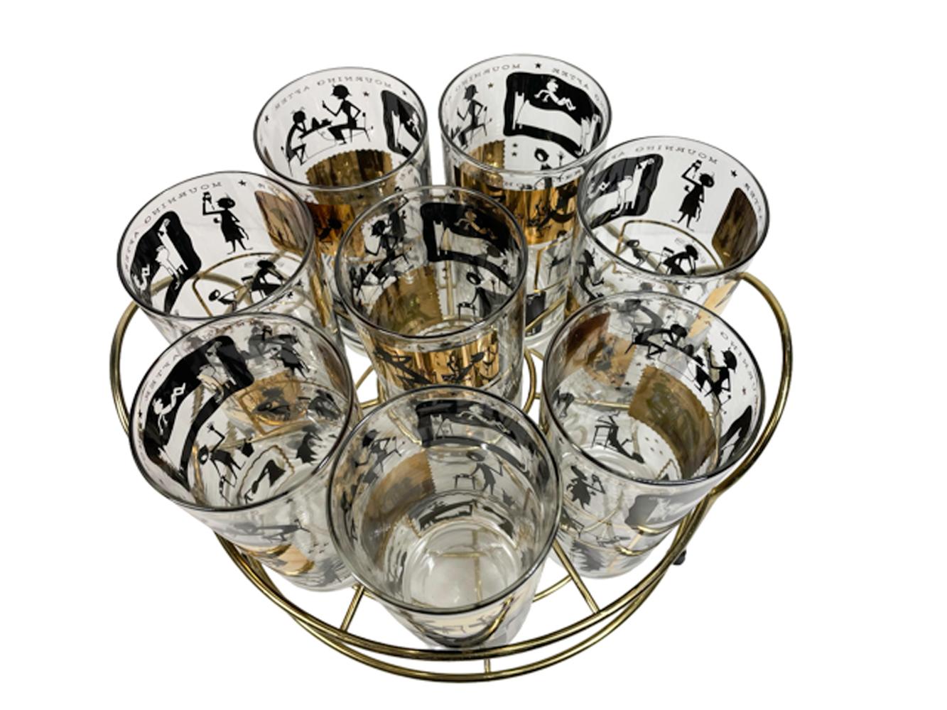 Set of eight Cera Glass highball glasses in a circular gold-tone caddy. Each of the glasses is decorated in 22 karat gold and black enamel with 3 rows of four scenes depicting people in various morning activities, suffering the effects of too much