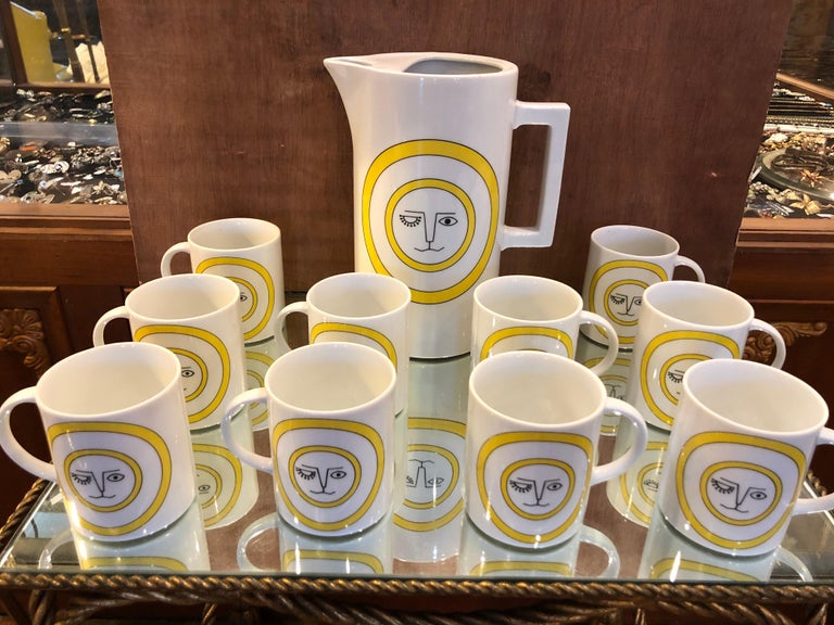Mid-Century Modern ceramic coffee or tea pot and mug set. Includes one large coffee or teapot and 10 matching mugs. With its whimsical Mid-Century Modern graphics of a winking eye sun lion reminiscent of Lisa Larsons ceramic work. Perhaps