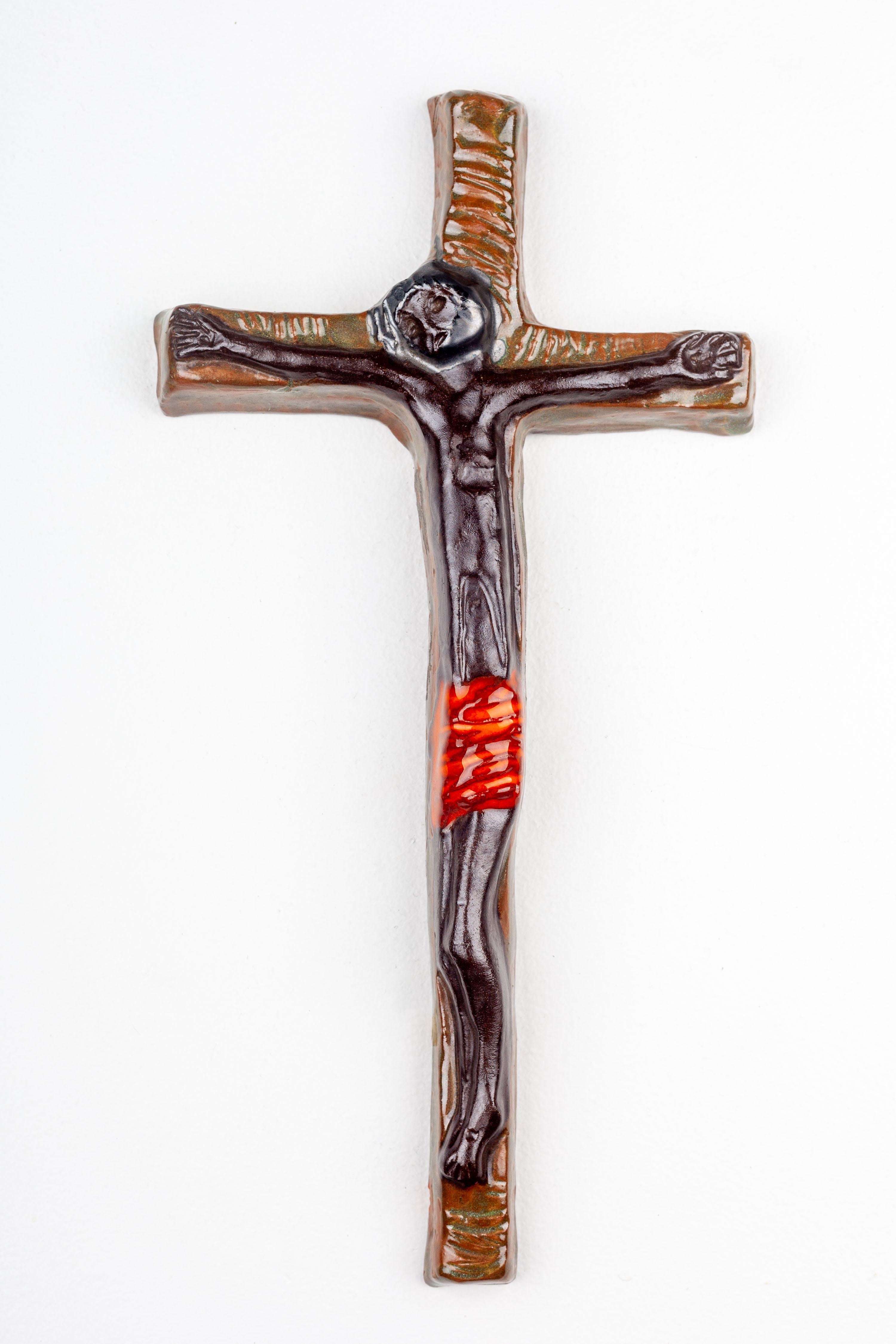 This mid-century modern wall cross is a notable example of European studio pottery from the 20th century, showcasing a blend of religious iconography with the era's distinctive artistic sensibilities. Crafted by hand, this ceramic piece is