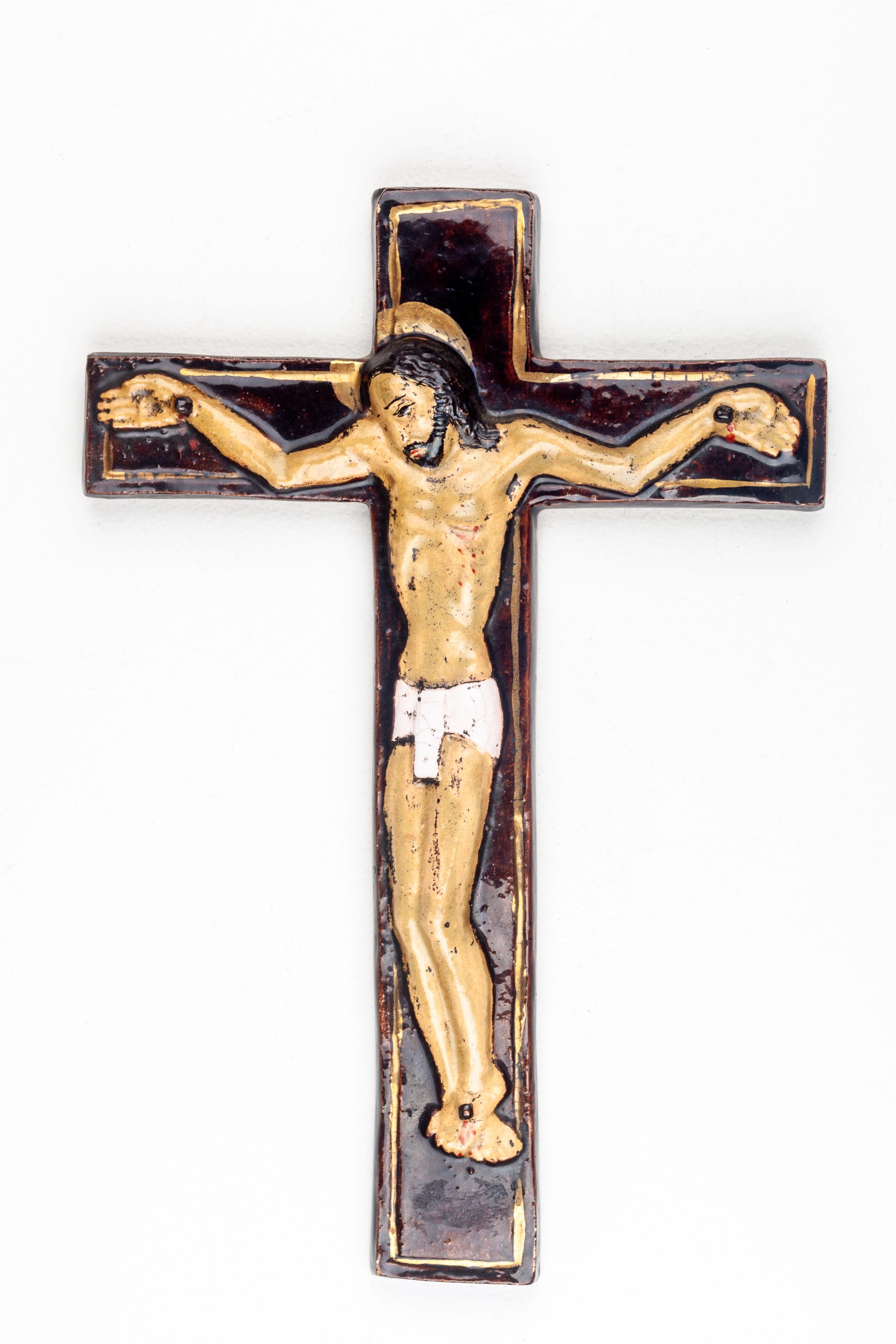 Dieses moderne Kruzifix aus der Mitte des Jahrhunderts ist ein ergreifendes Beispiel europäischer Studiotöpferei, das die spirituelle Gravitas religiöser Kunst mit den ästhetischen Grundsätzen der Epoche verbindet. Die Figur des Christus ist in