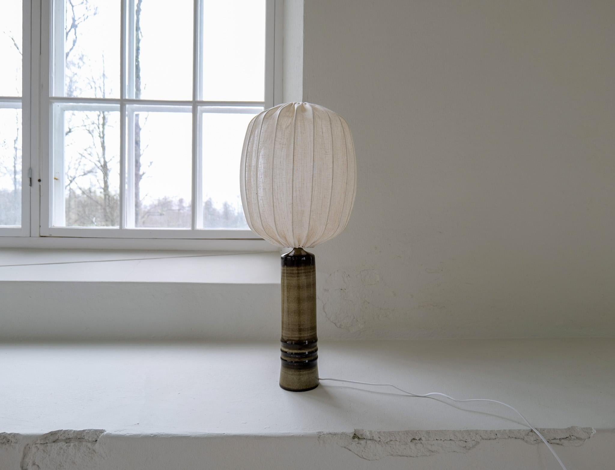 Large earthy toned glazed stoneware table lamp by Olle Alberius for Rörstrand, Sweden, 1970s.
Signed on the base. The color of the glaze is wonderful and gives a natural earthy look. This one has been gifted with a large new shade. 

Very good