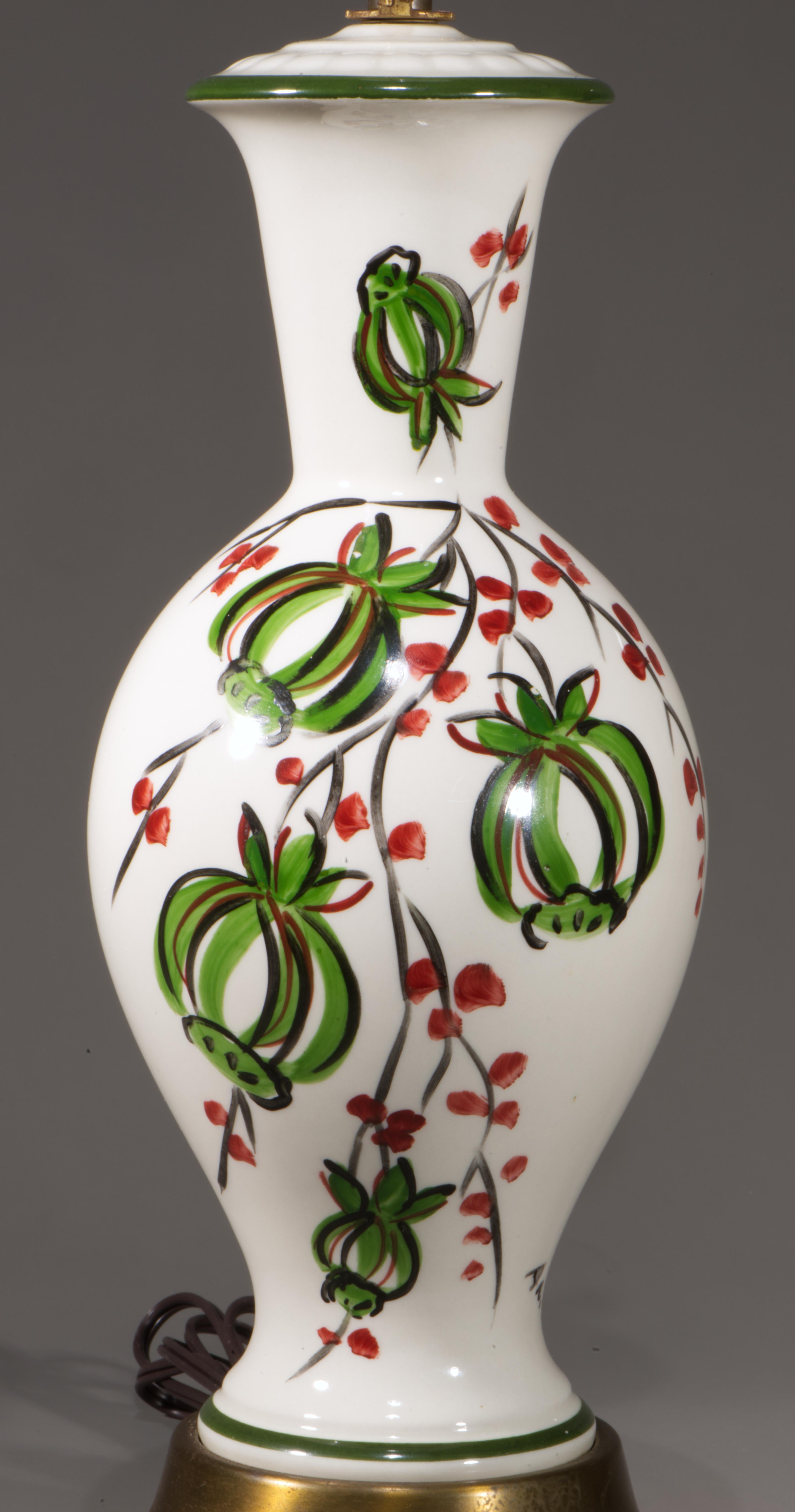 Escultural lámpara de sobremesa vintage con base de urna o balaustre, decorada con un motivo abstracto de flores y ramas pintado a mano. Los colores negro, verde oscuro y rojo burdeos de la decoración destacan sobre el nítido esmalte blanco del