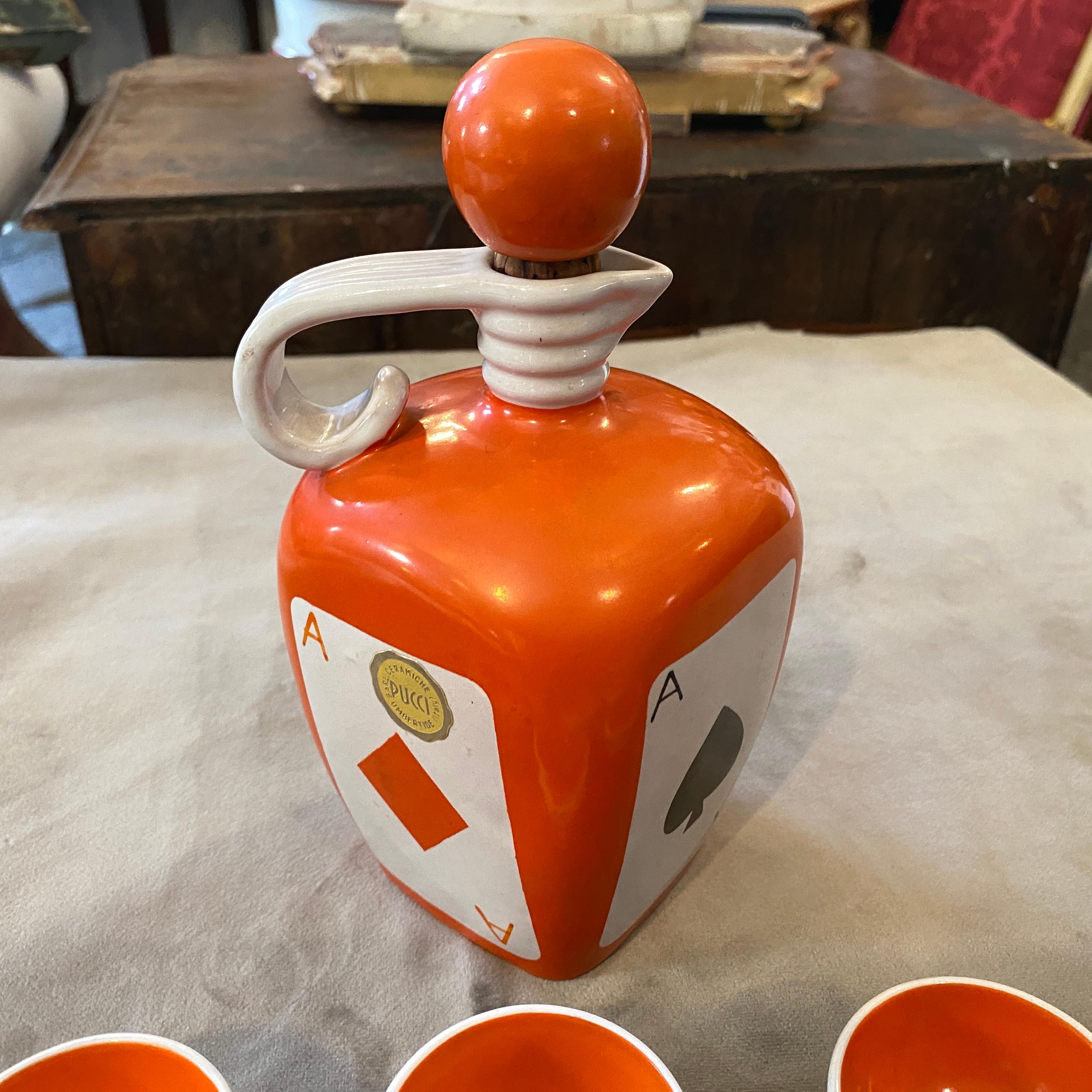 A particular orange black and white ceramic liquor set made by Italian famous manufacturer Pucci. The bottle is decorated with poker cards suits.