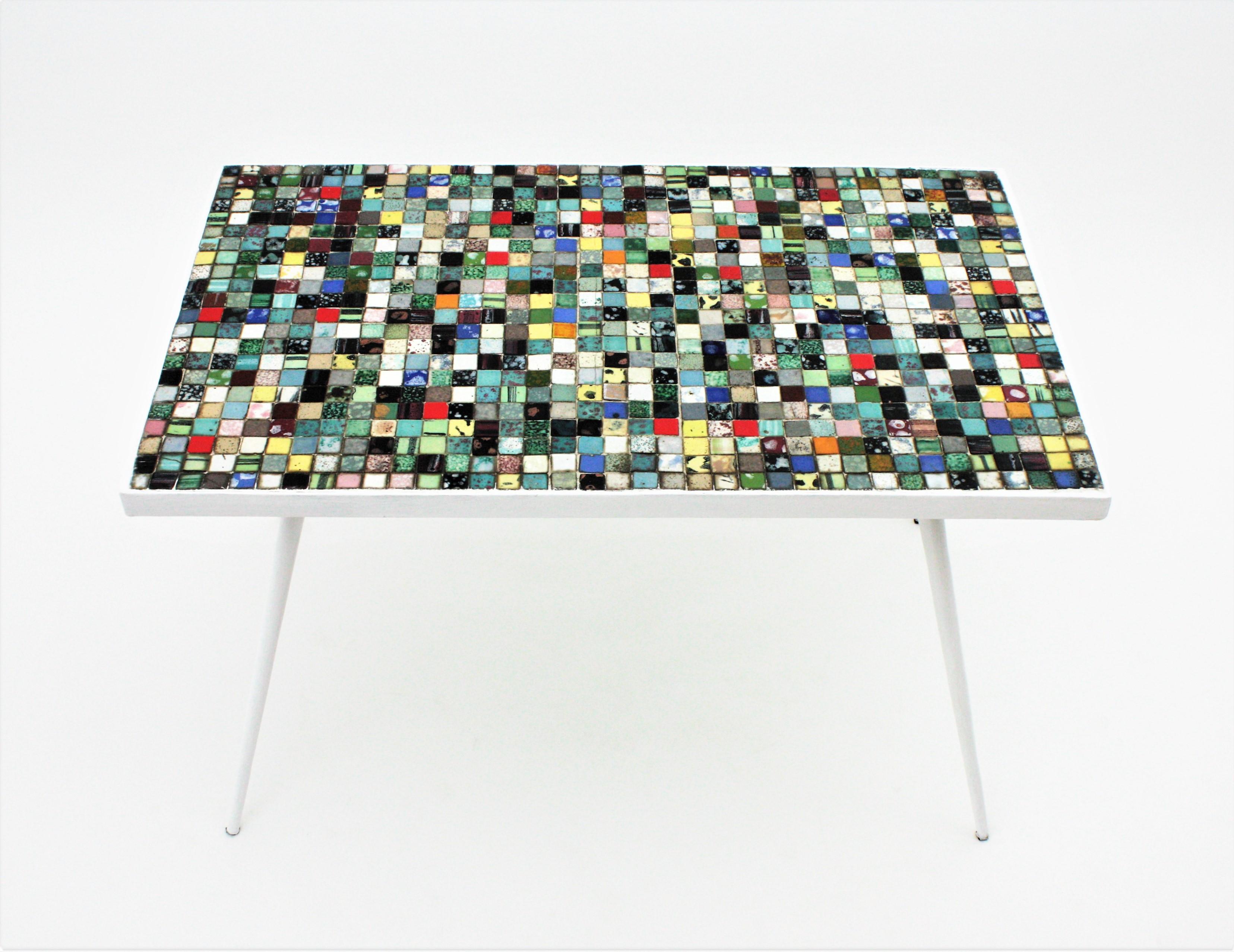 Beautiful Mid-Century Modern table with ceramic mosaic tile top and iron base. Spain, 1950s
This coffee / cocktails table or end table features a ceramic grid mosaic with tiles in different colors standing on a four footed iron base painted in white