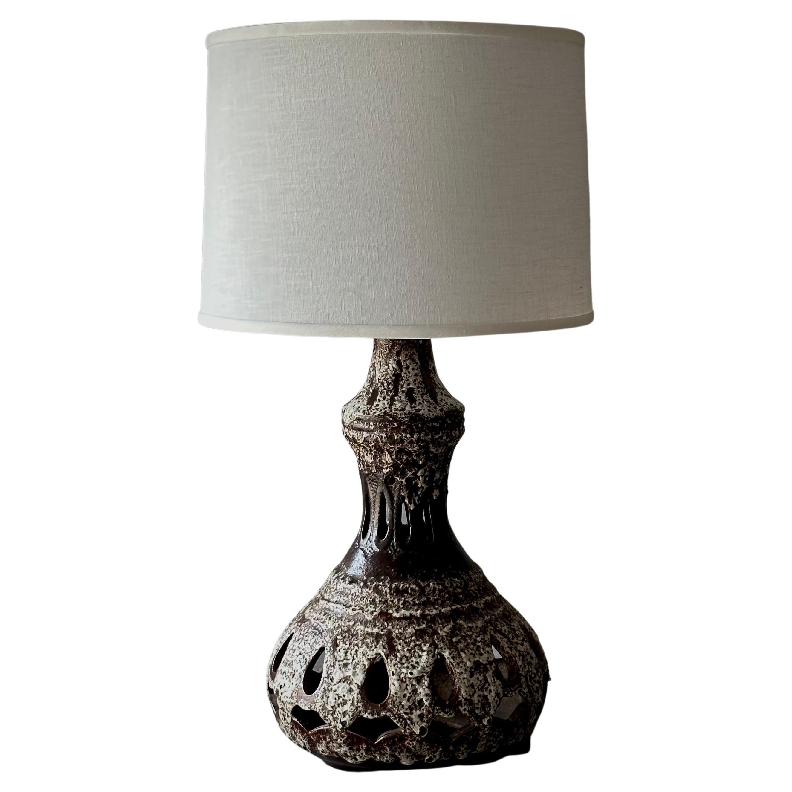 1970s West German ceramic table lamp with white and dark brown glazing, perforated curvilinear shape and unique seafoam-like textured surface. Includes custom ivory linen shade. 

Germany, circa 1970

Dimensions: 17W x 17D x 32H.