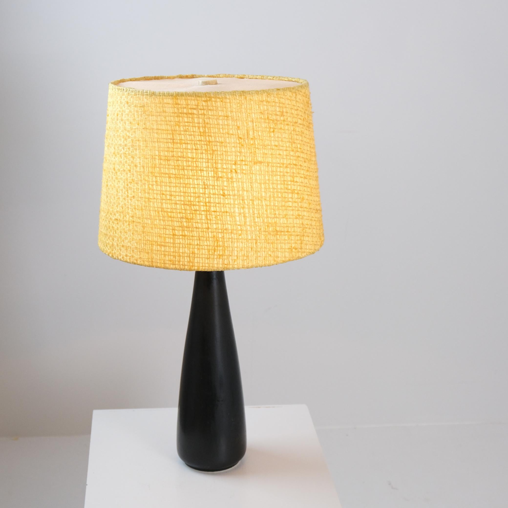 A lovely vintage ceramic table lamp in black, brass and original yellow shade. The lamp is quite tall for a table lamp with a height of 47cm without the shade (66cm with). The lamp is most probably manufactured by Orno which produced a few Arabia