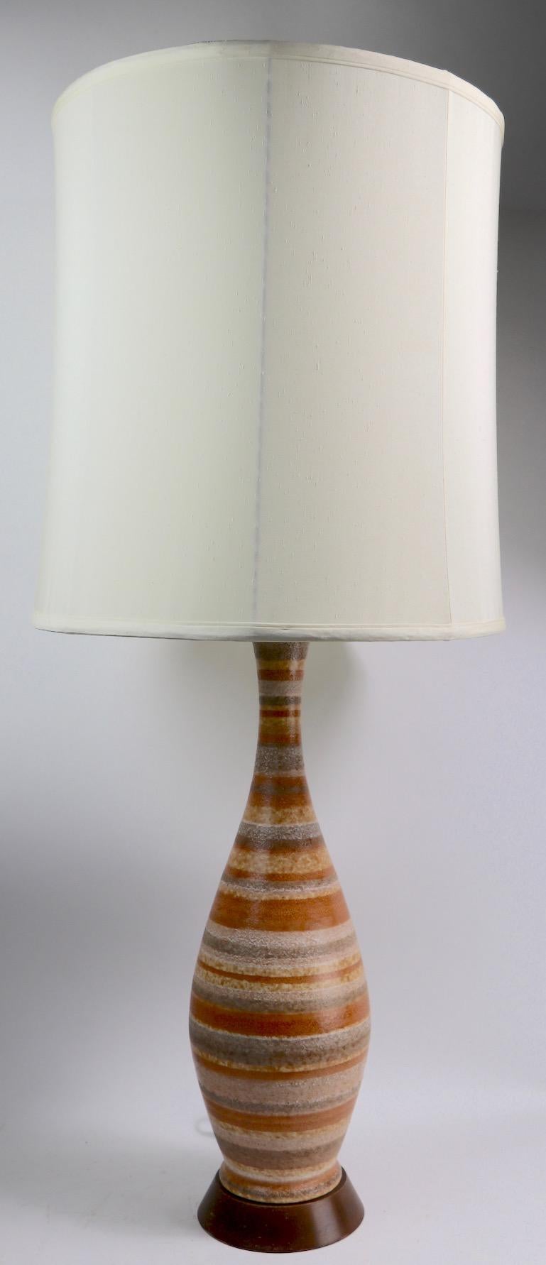 Stylish Mid-Century Modern pottery table lamp with stripped brown tone body on walnut plinth base. Original, clean and working condition, includes original turned wood finial, shade not included. Currently wired to accept a standard size screw in