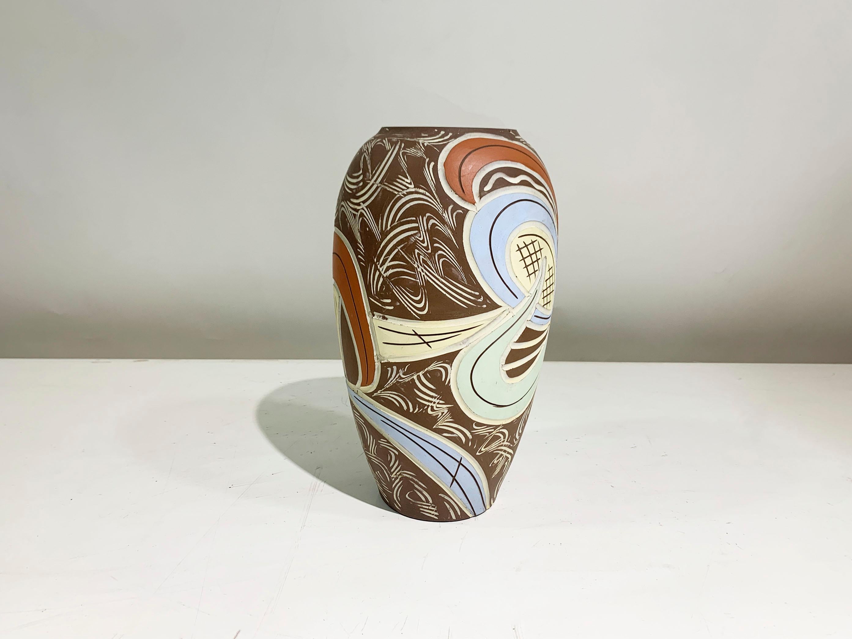 Il vaso presenta un design astratto e geometrico composto da linee e forme geometriche, con l'uso di colori pastello verde, blu, arancione e giallo.
I disegni sono composti principalmente da grandi forme curve e da linee intricate e vorticose. I