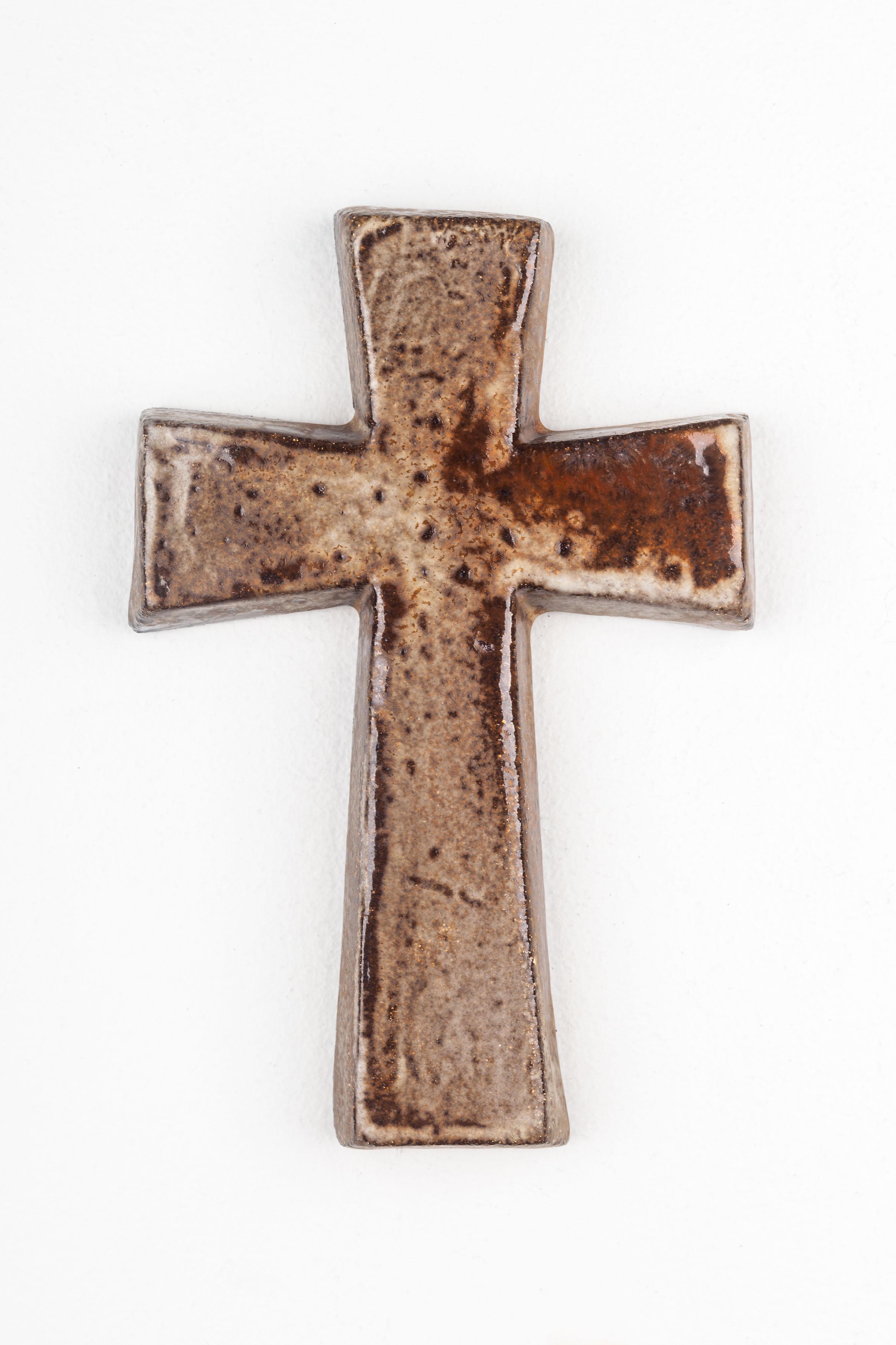 This mid-century modern wall cross is a quintessential example of European studio pottery from the 1950s. Handcrafted by a skilled artisan, it showcases the raw beauty of ceramic artistry that was prevalent during the post-war era. The cross's