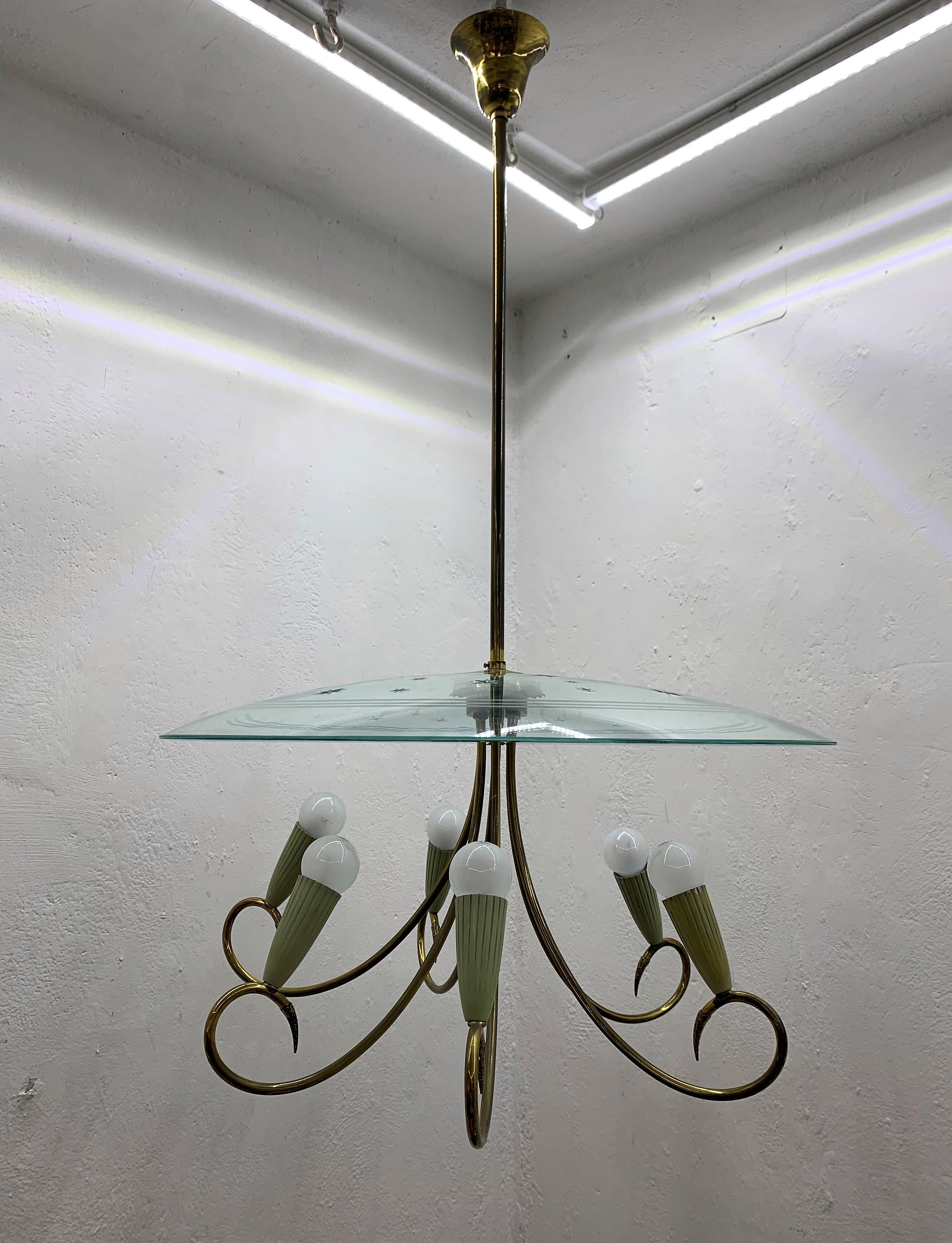 Large Mid-Century Modern six-light chandelier in the style of (attributed) to Pietro Chiesa and Fontana Arte in the shape of an UFO or Flying Saucer, in brass and carved curved glass displaying stars, Italy, 1940's.
The brass hardware has not been