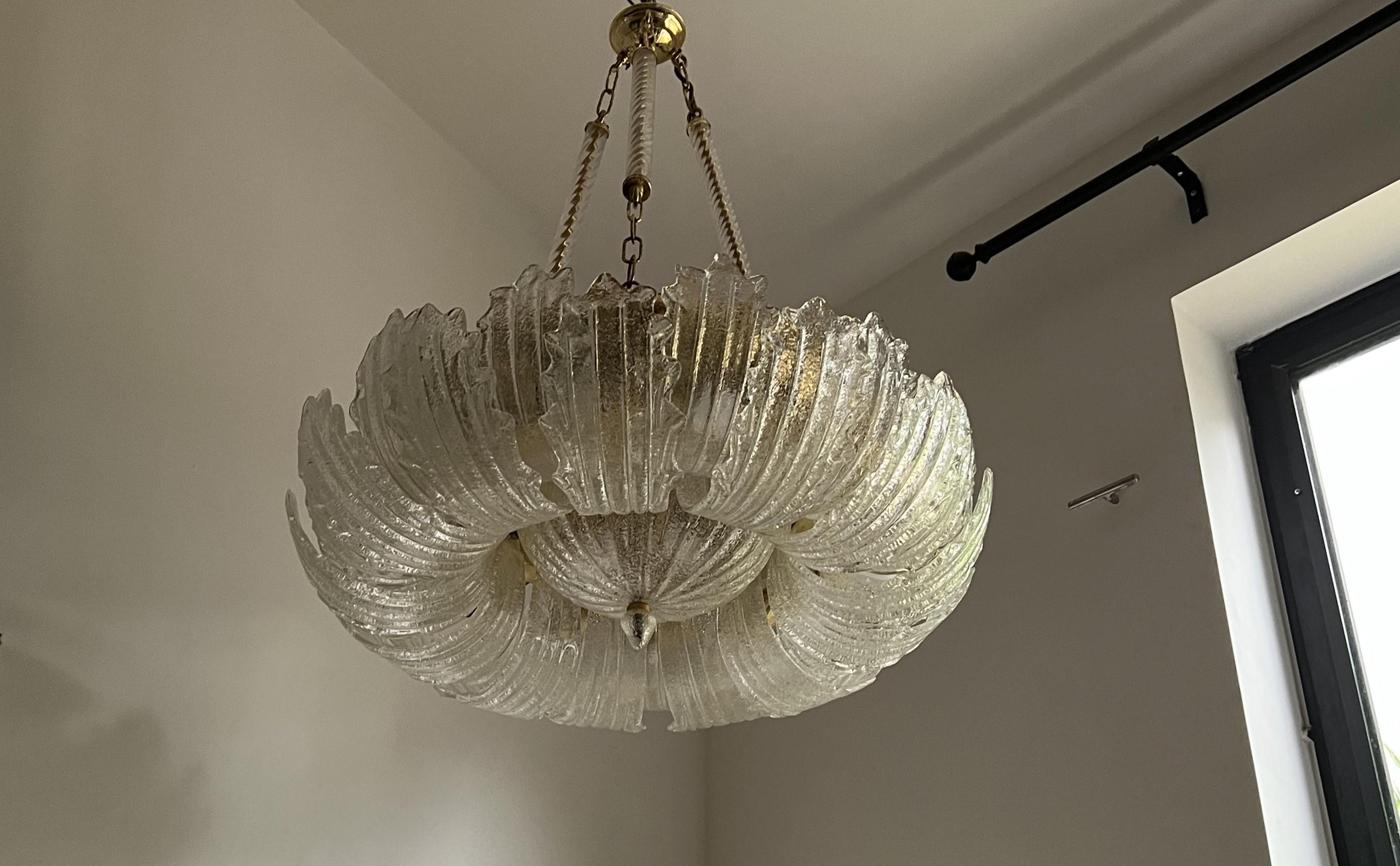 Beautiful and large Mid Century Modern  chandelier, manufactured in lacquered metal, brass and hand-blown Murano glass.
Composed of 26 large murano glass leaves and one central bowl, all executed in a clear glass with one side having glass dust