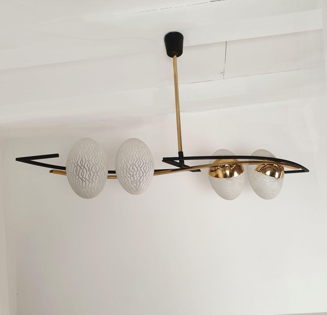 Mid Century Modern chandelier, by Maison Arlus, France 1960s.
The French chandelier is made of brass, black metal and 4 glass shades.
Each glass egg is nesting one light bulb.
The chandelier is professionally rewired for the US ( or for Europe upon