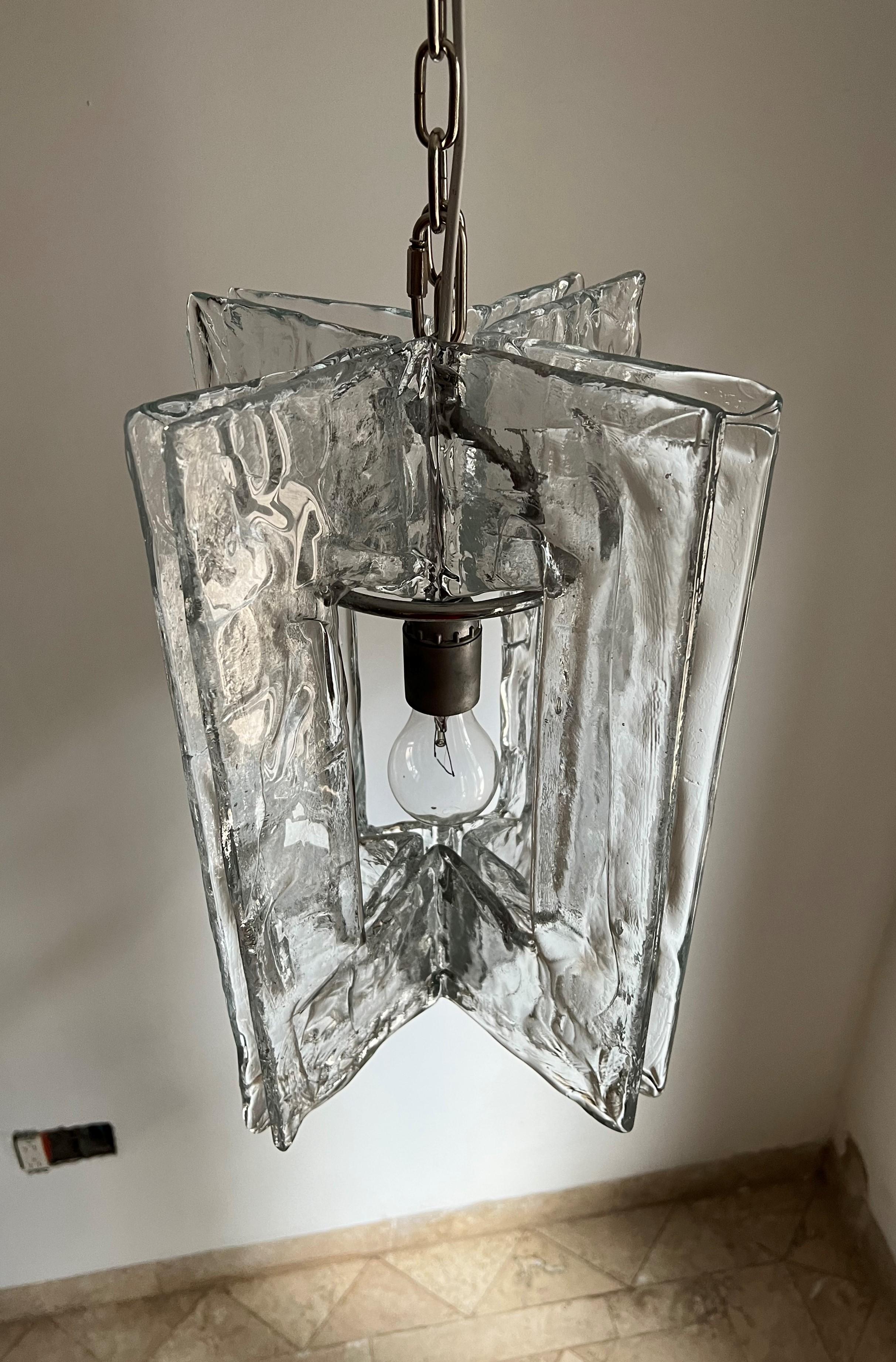 Space age chandelier manufactured in chromed metal and 4 large pieces of clear Murano glass.
It takes 1 e27 bulb.
Made in Murano Italy circa 1970 by Mazzega under the direction of Carlo Nason.
Length of each glass slab is 40 cm and the diameter