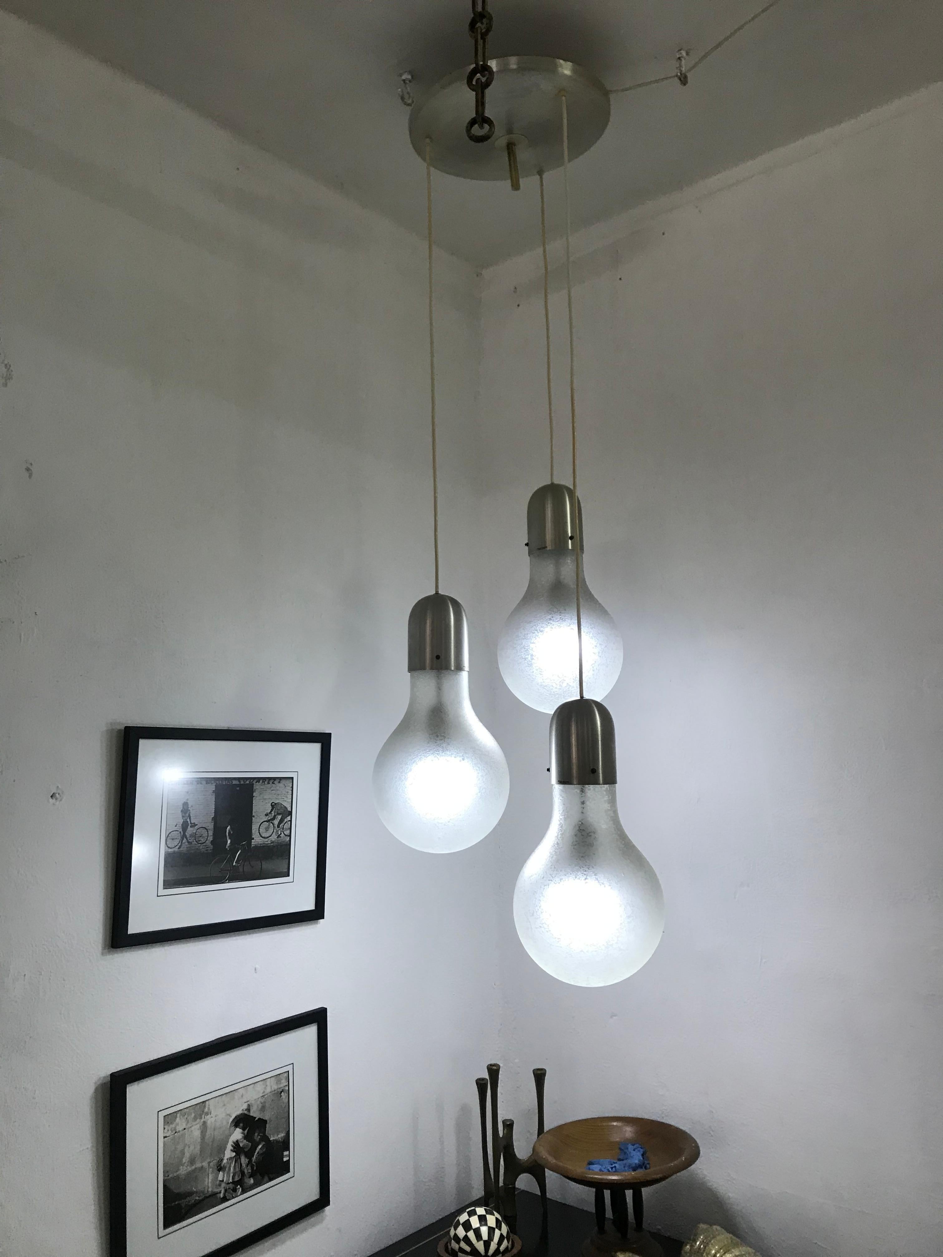 Mid-Centruy Modern chandelier consisting of 3 pendant lights in the shape of oversized light bulbs, manufactured by Stilux Milano in Italy ca. 1970s.
The globes are done in the 